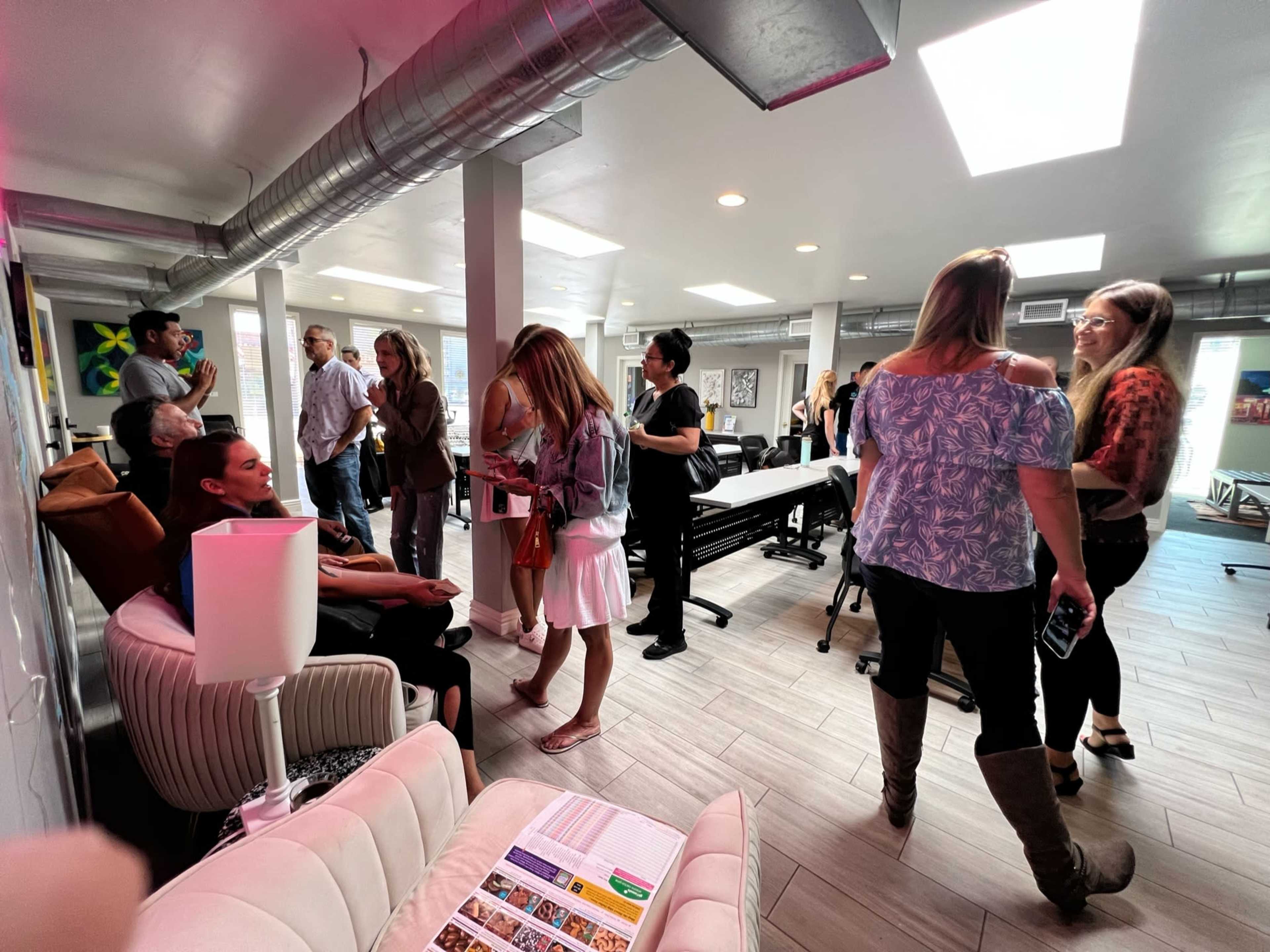 A group of people interacting in a modern office space with a mix of seating areas and tables.
