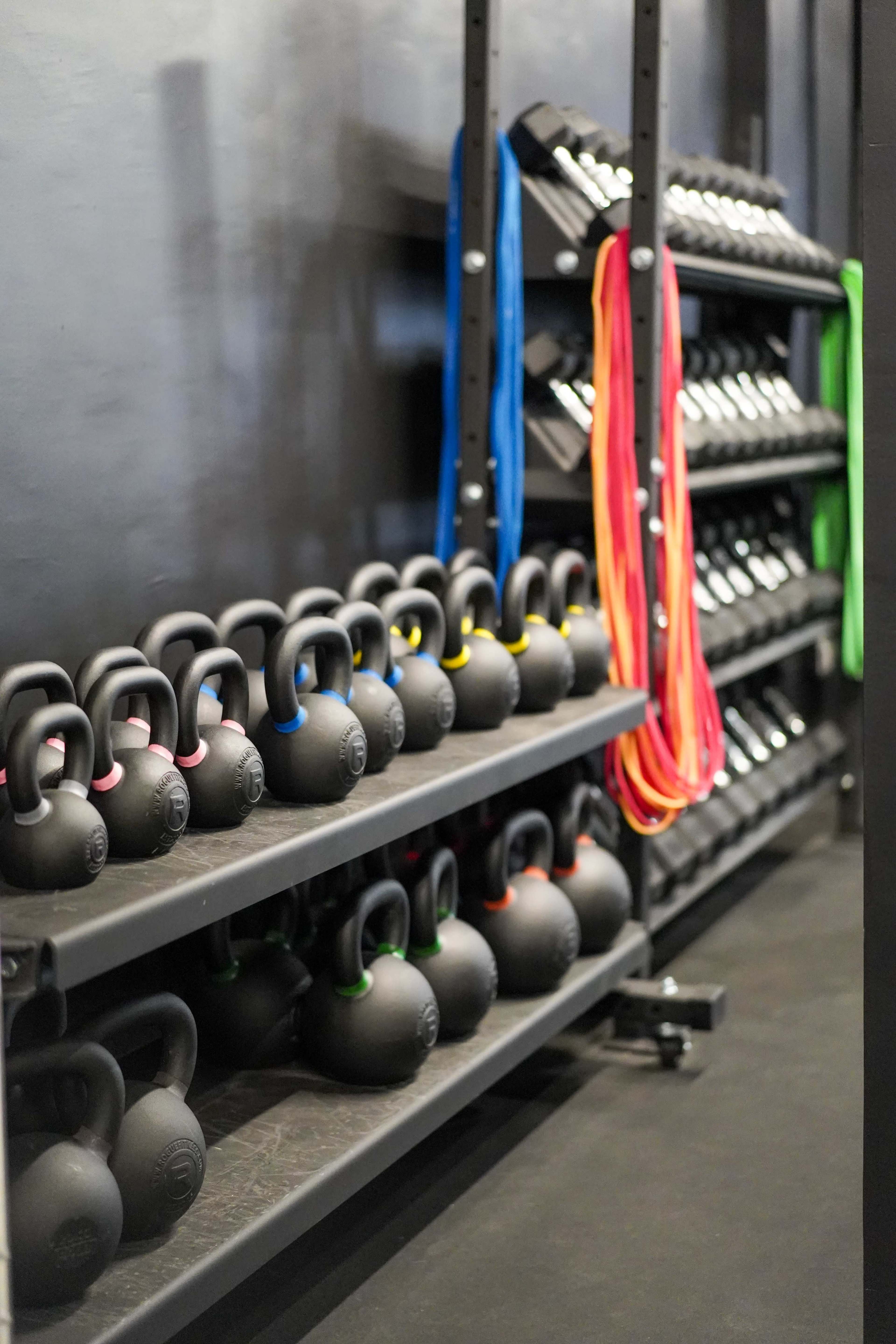 A fitness area with neatly arranged kettlebells and resistance bands on shelves.