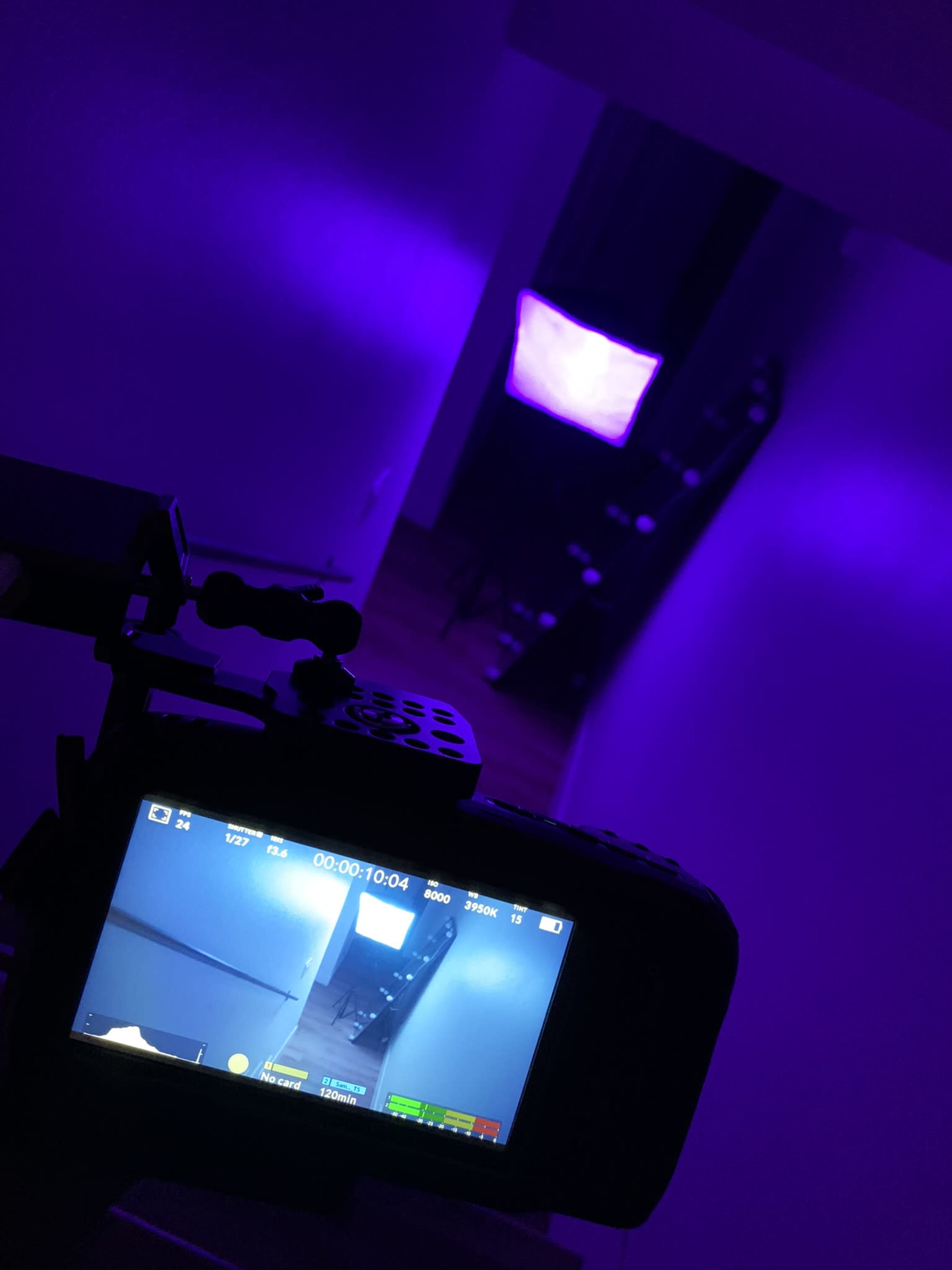 A camera is focused on a dimly lit hallway with purple lighting and a softbox in the background.