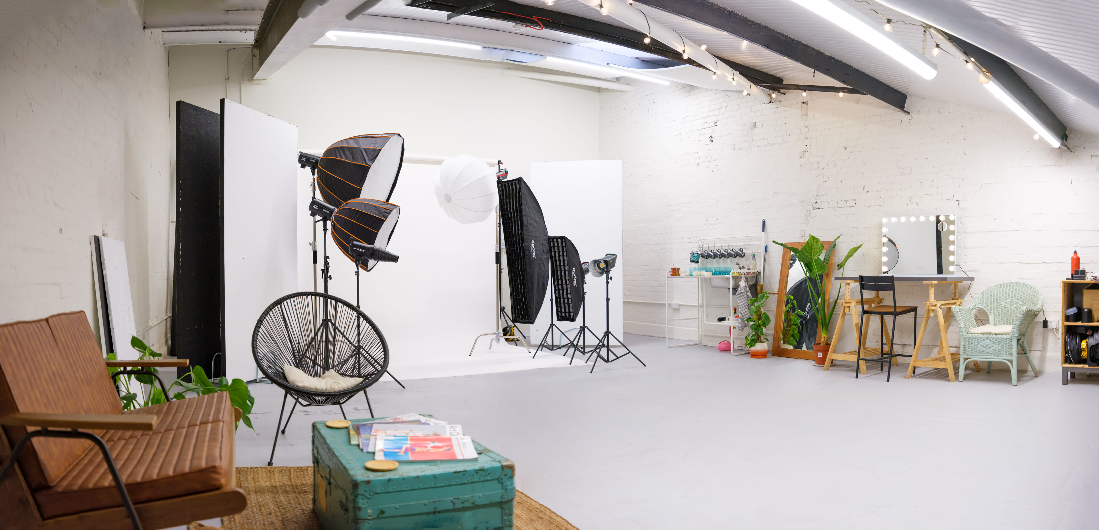 A photography studio equipped with lighting equipment, backdrops, and various furniture pieces arranged around the space.