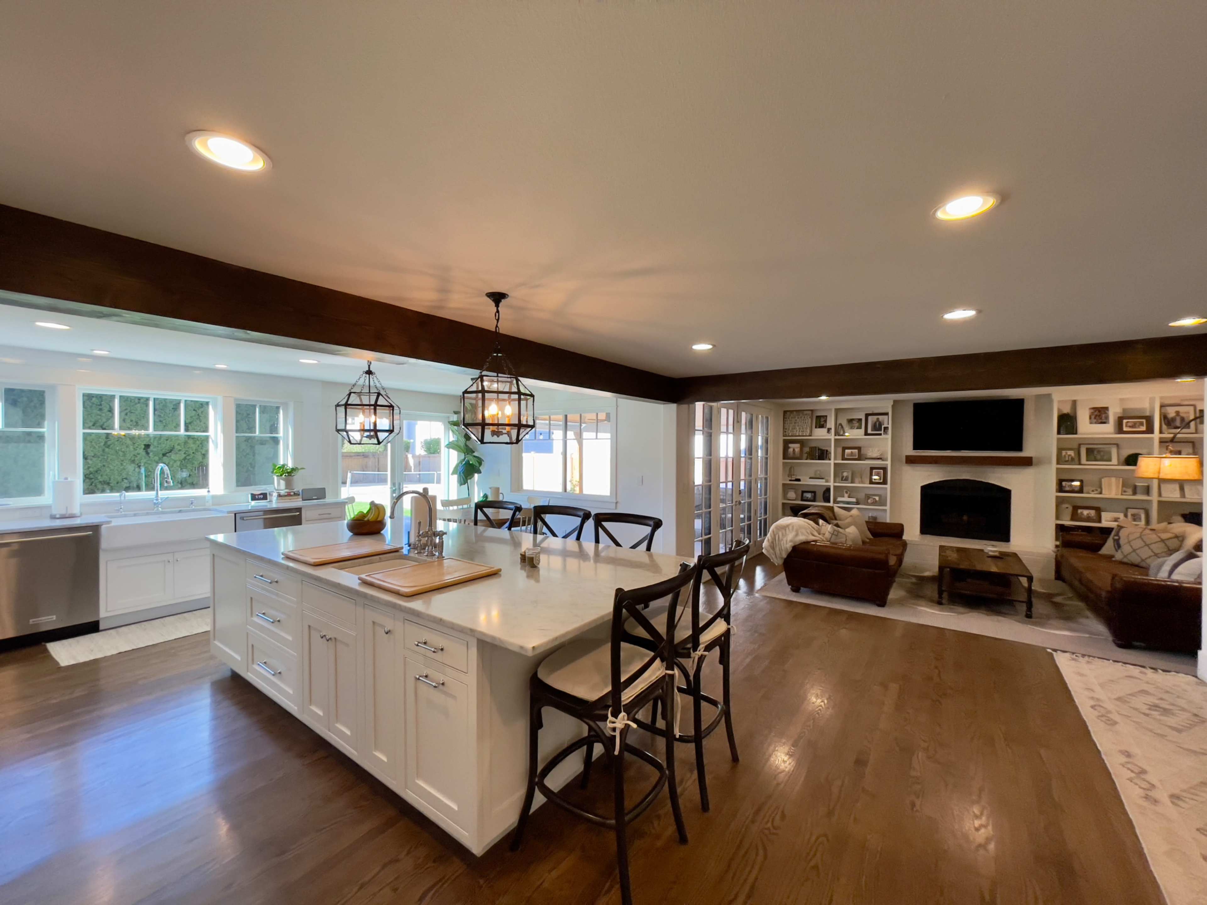 A spacious kitchen and living area featuring an island with bar stools, a large window, and a cozy seating arrangement with a fireplace.