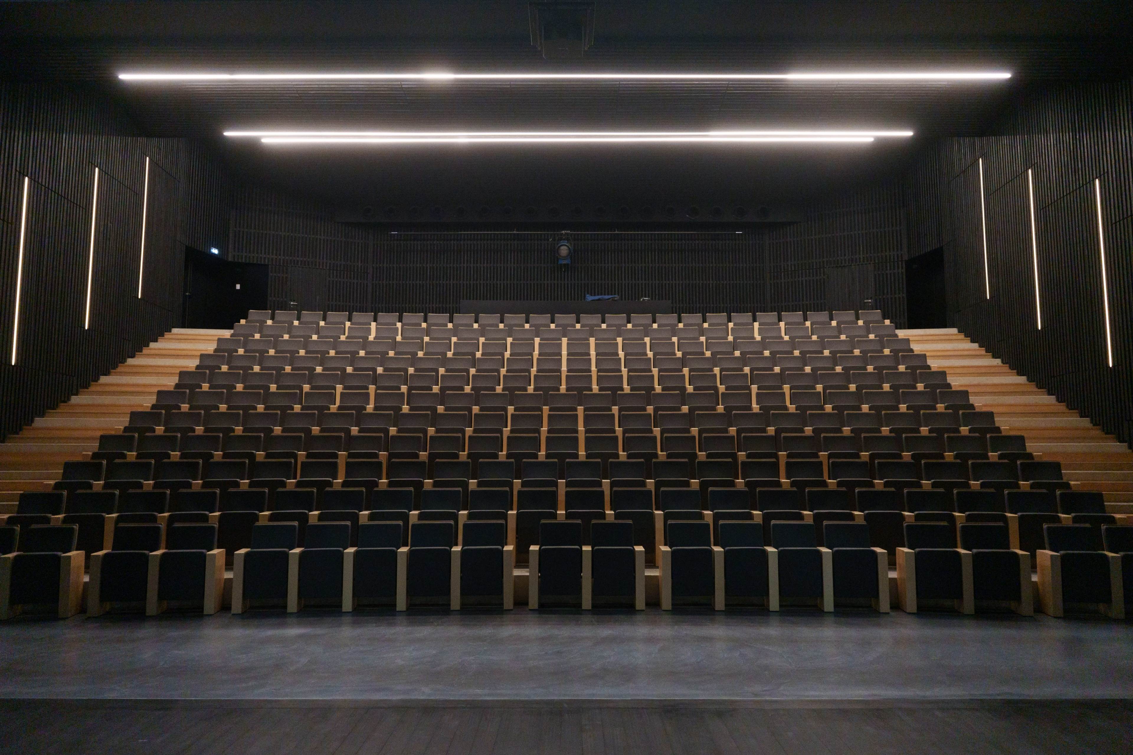 A modern auditorium with tiered seating arranged in a symmetrical layout.