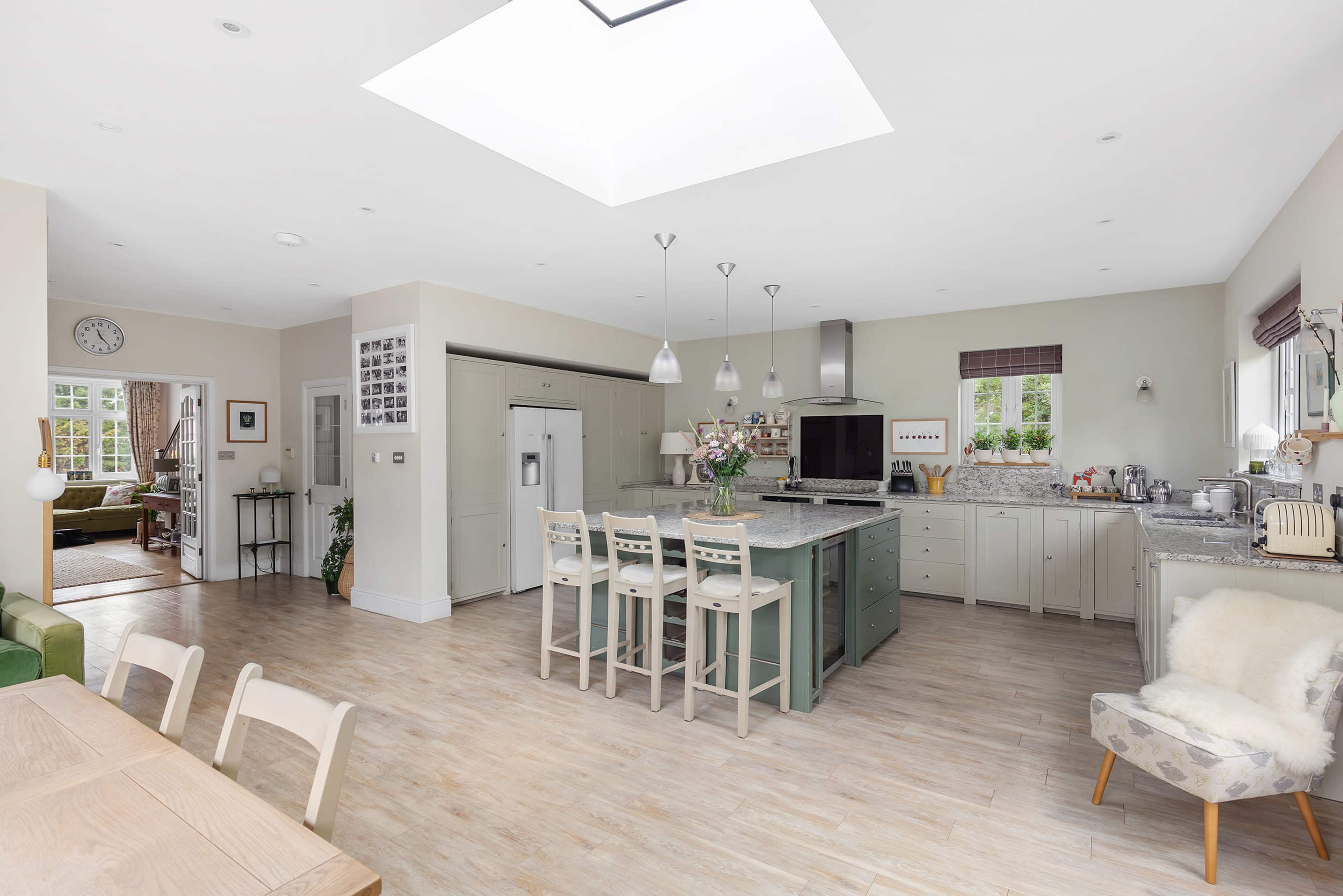 A spacious kitchen features an island with seating, modern appliances, and ample natural light from a skylight.