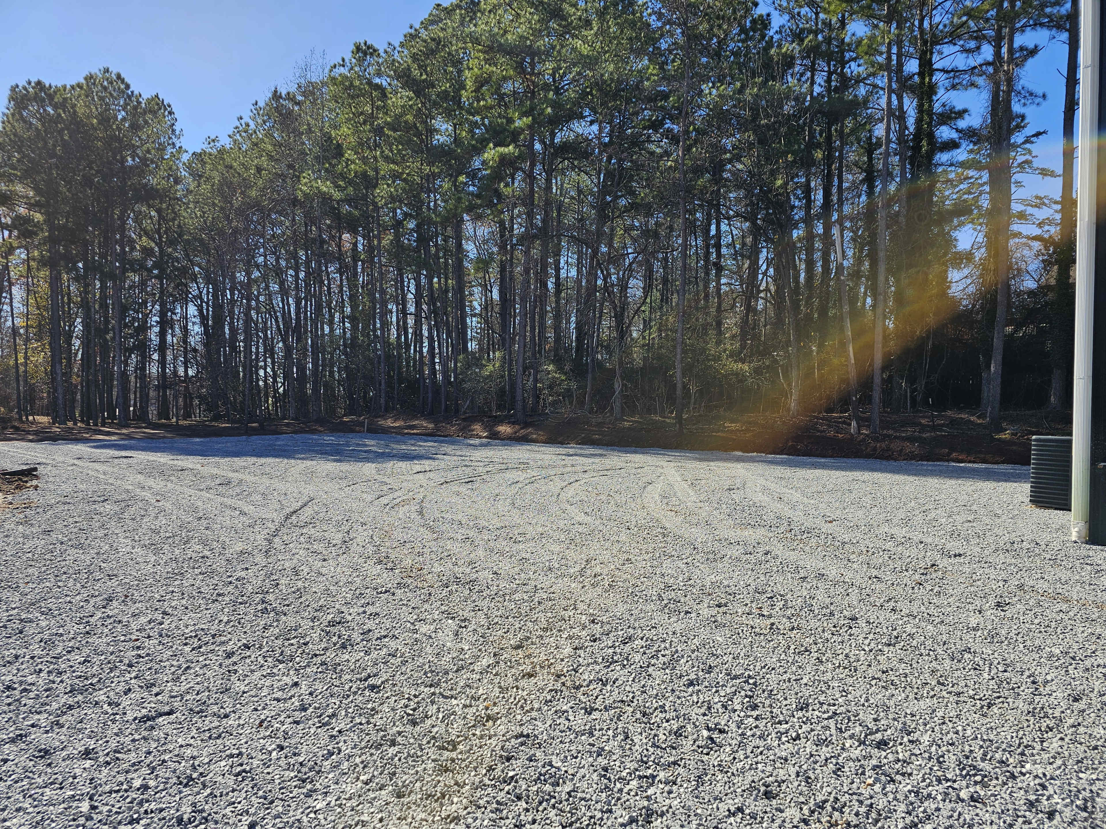 The image shows a gravel area surrounded by trees in a wooded setting.