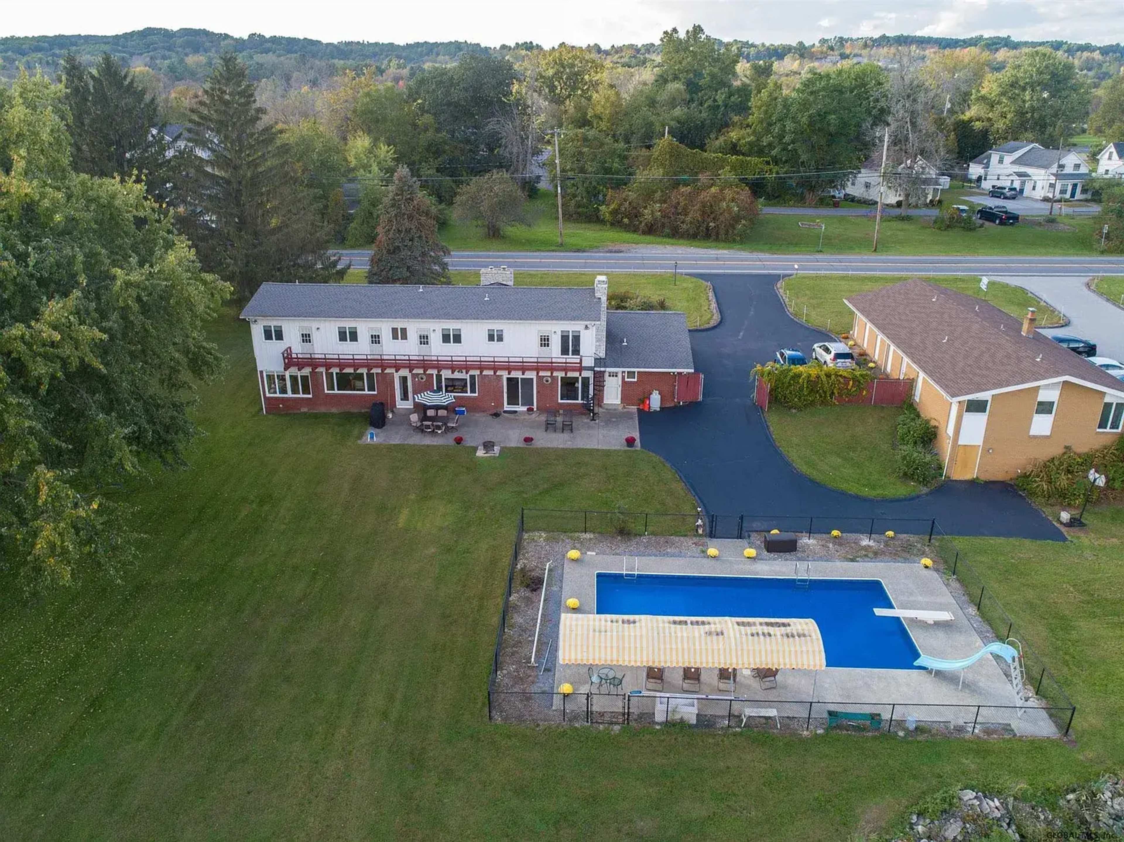 The image shows a large residential property that includes a two-story house, a fenced swimming pool, and surrounding grassy areas.