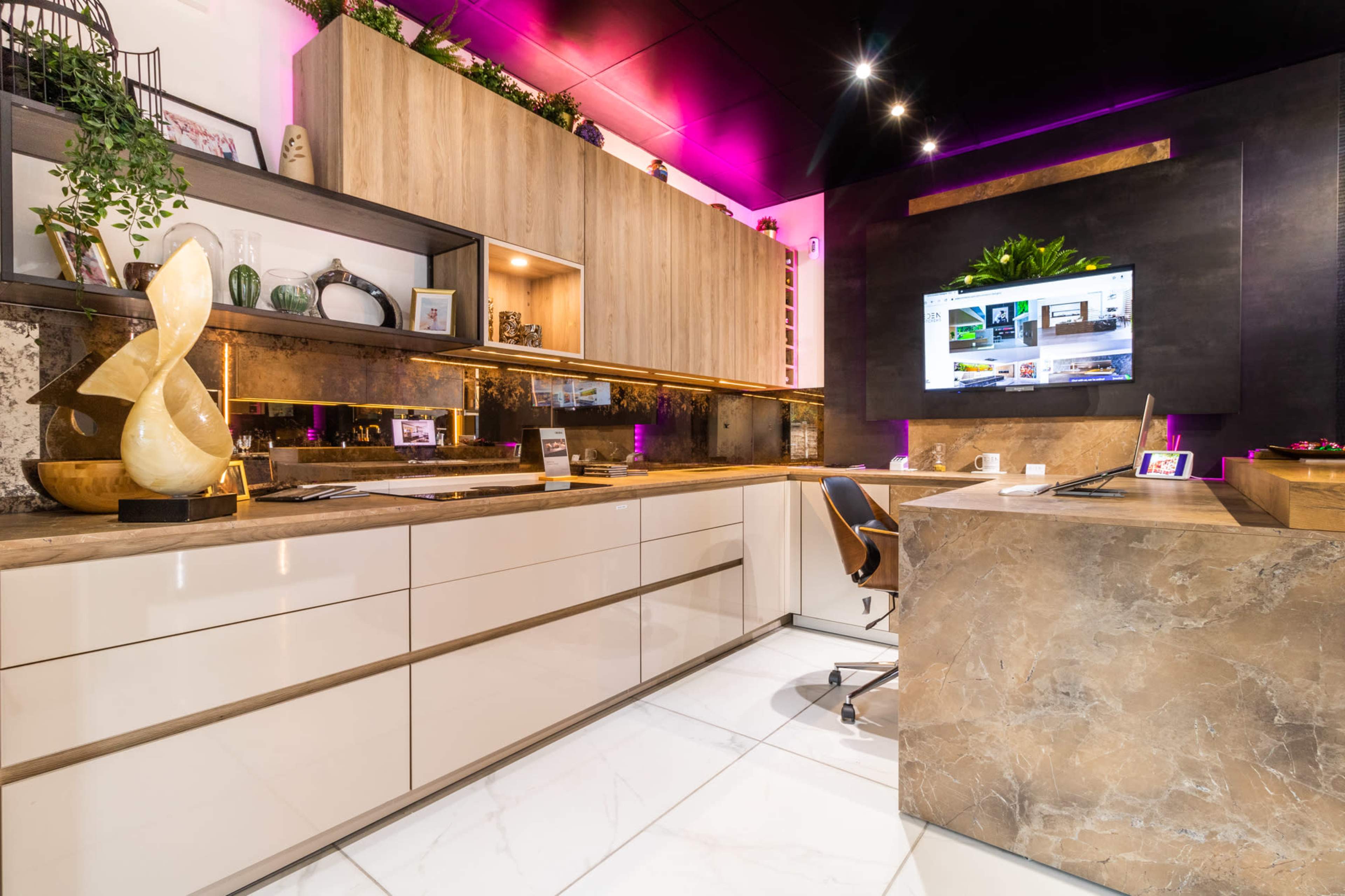 A modern office space features sleek cabinetry, a large screen, and a streamlined desk with decorative elements.
