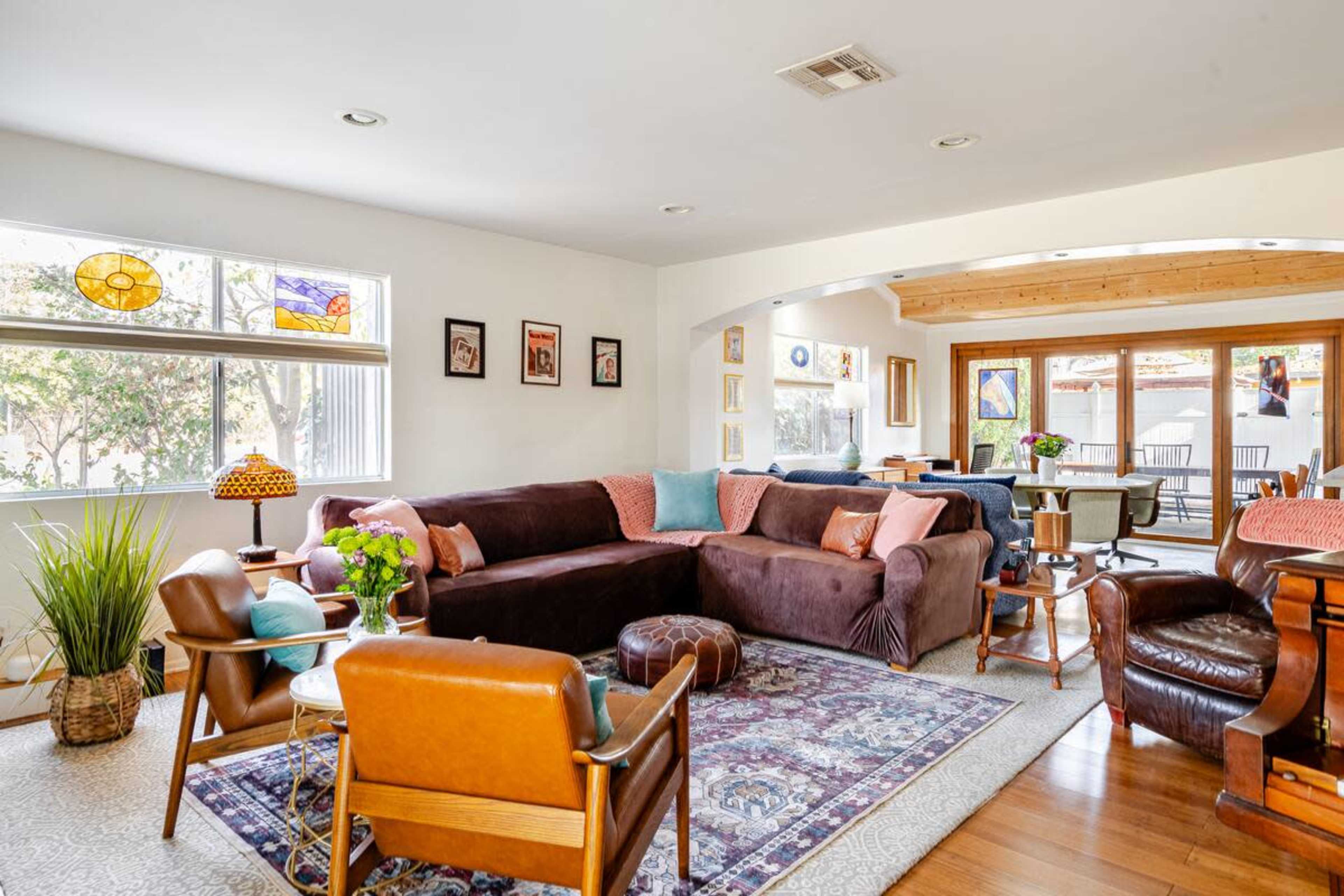 The image depicts a spacious living area with a large sectional sofa, wooden furniture, and a variety of decorative elements.