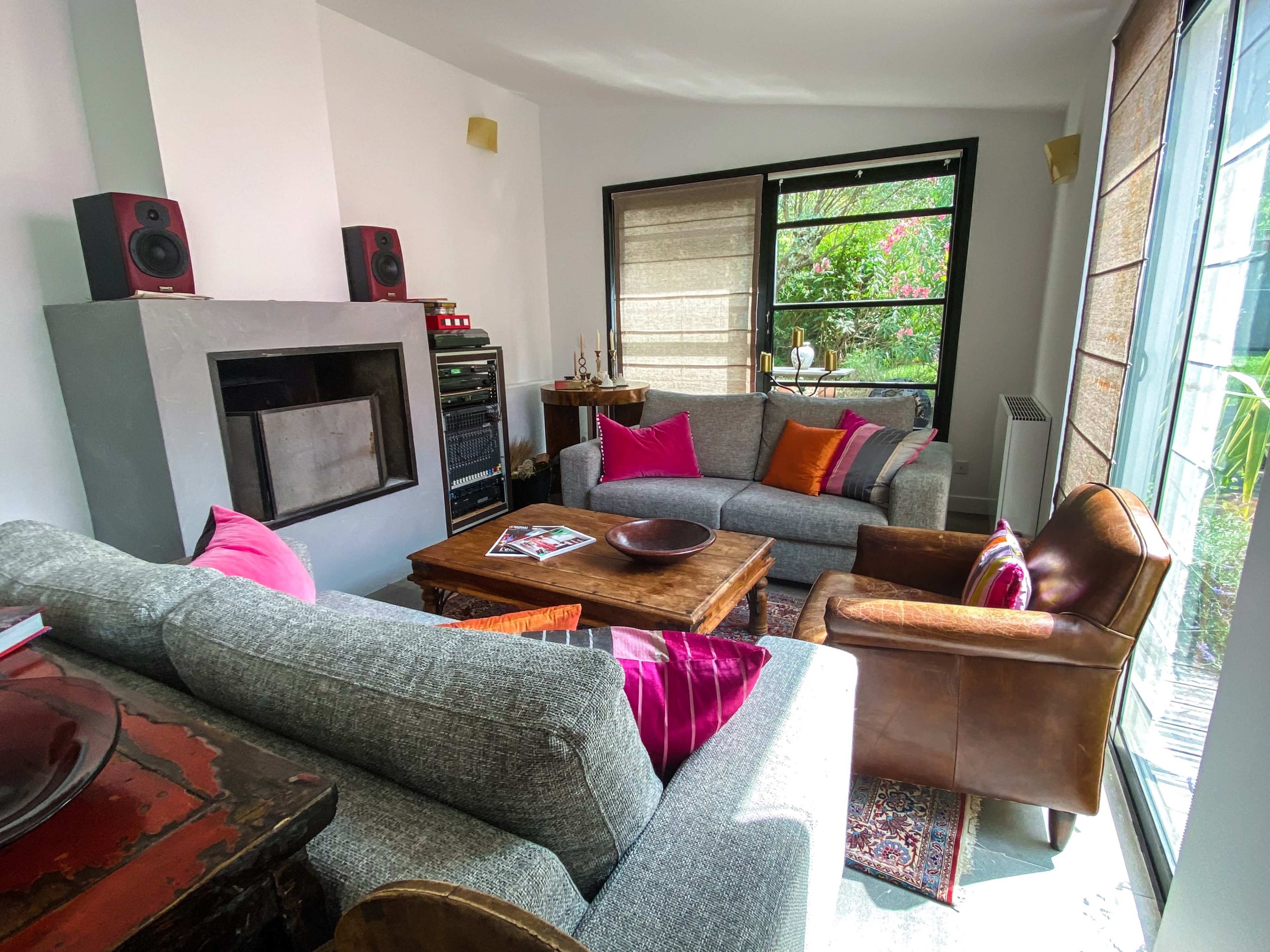 A cozy living room with two gray sofas, a brown leather armchair, a wooden coffee table, and various decorative elements.