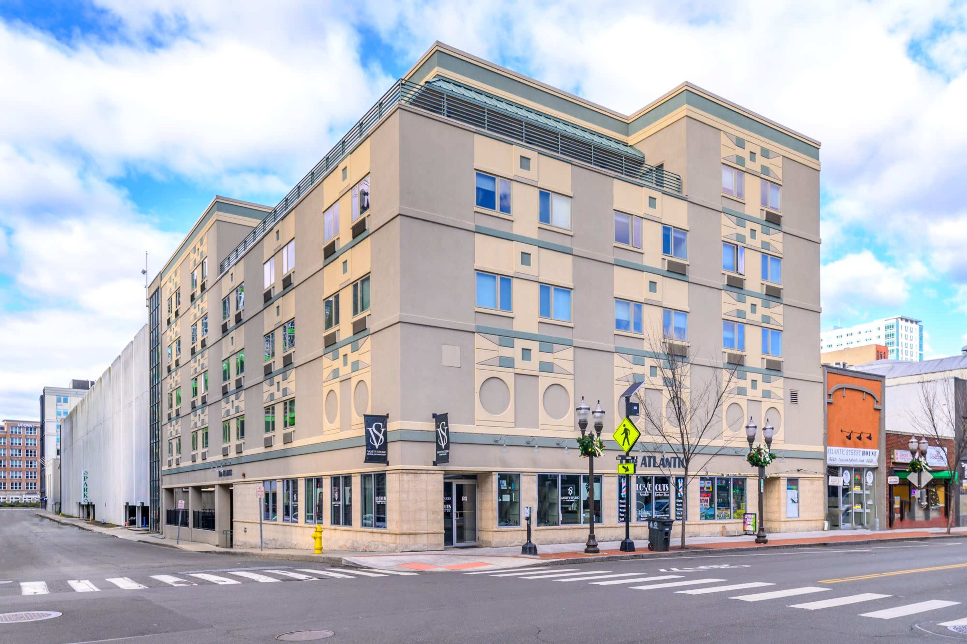 A four-story commercial building with a modern facade, located on a street corner, featuring windows and signage.
