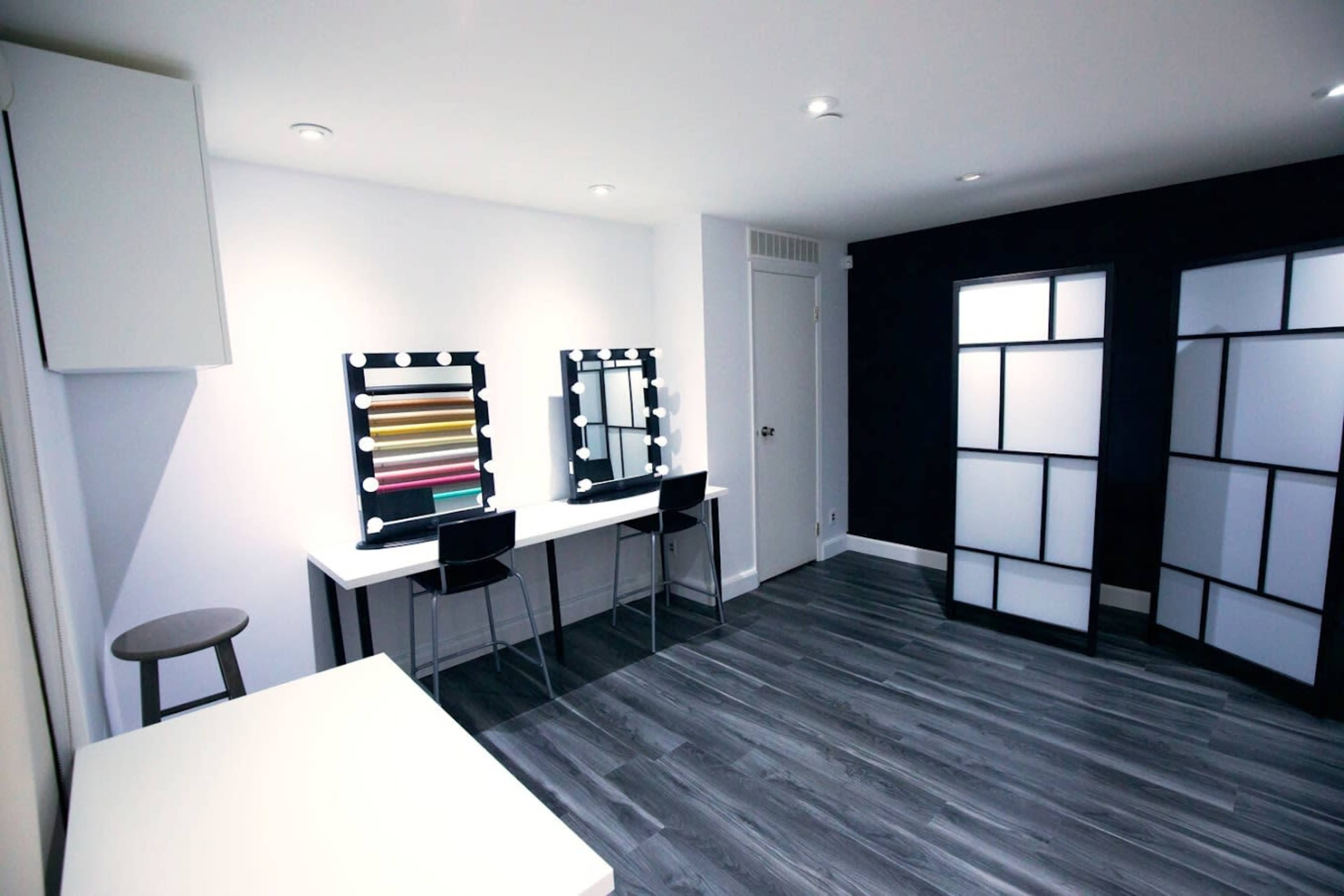 A well-lit dressing room with two vanity mirrors, a table, and a partition.