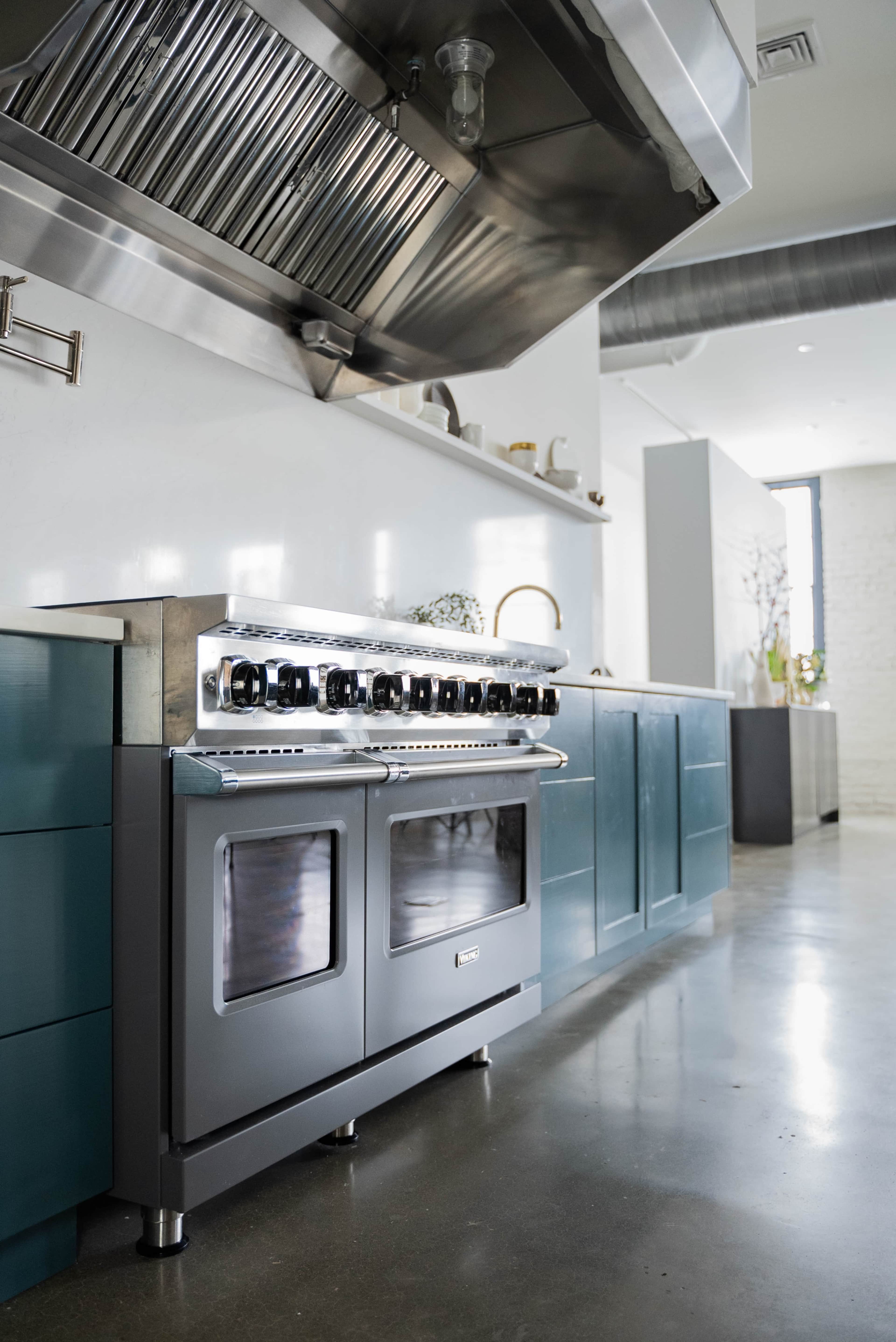 A modern kitchen features a stainless steel gas range with multiple burners and a sleek blue cabinetry.