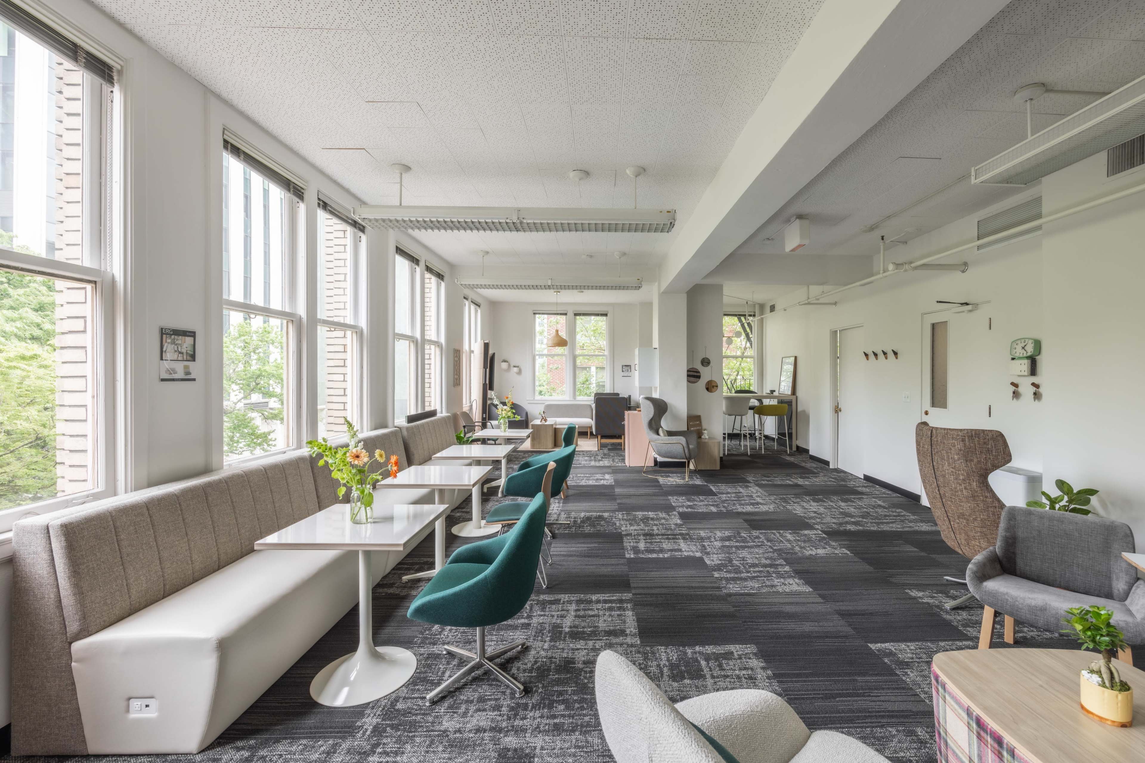 A spacious modern lounge area with large windows, various seating options, and a mix of tables and chairs.