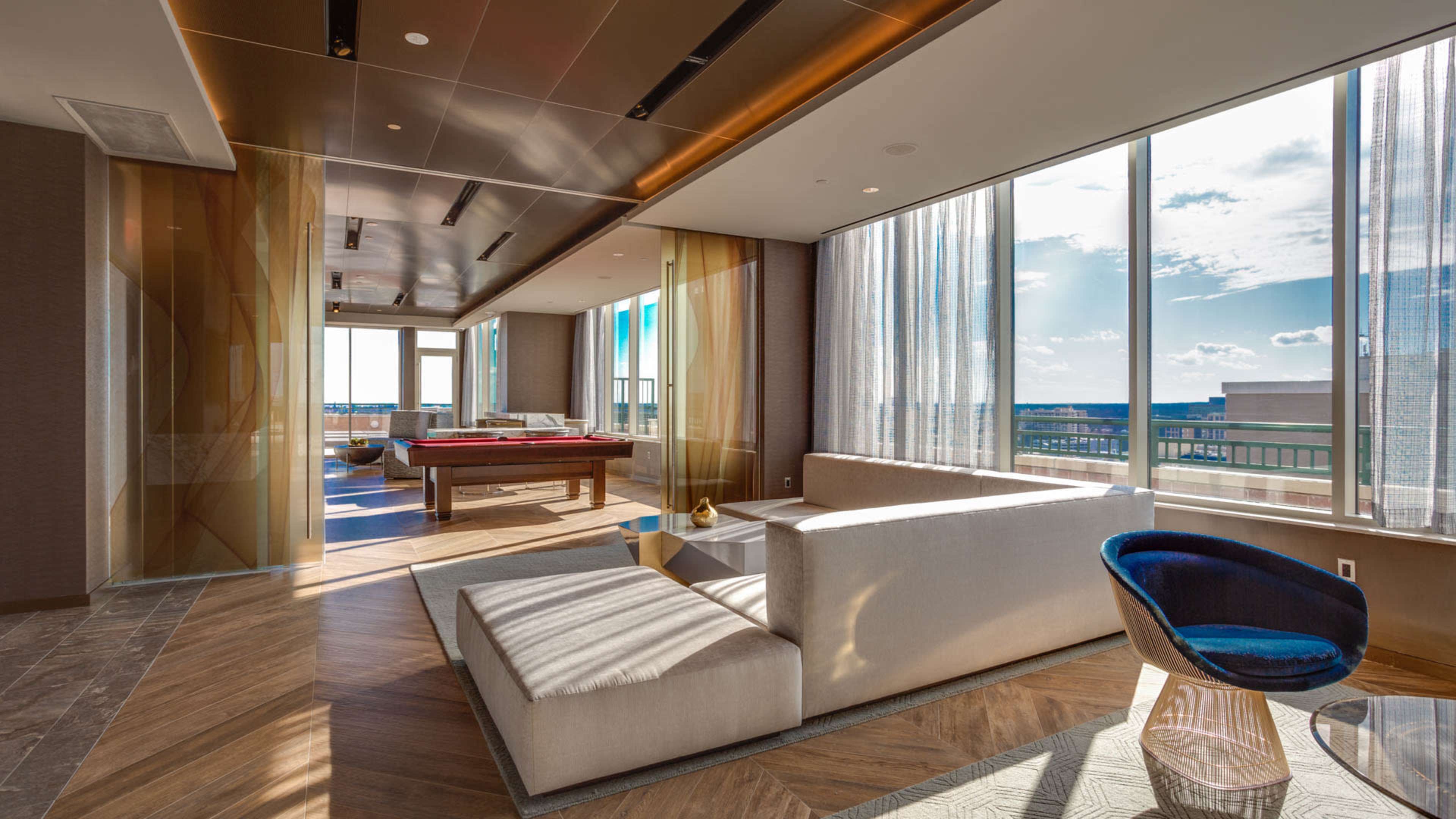 A modern, spacious lounge area features large windows, a pool table, and a mix of seating arrangements.