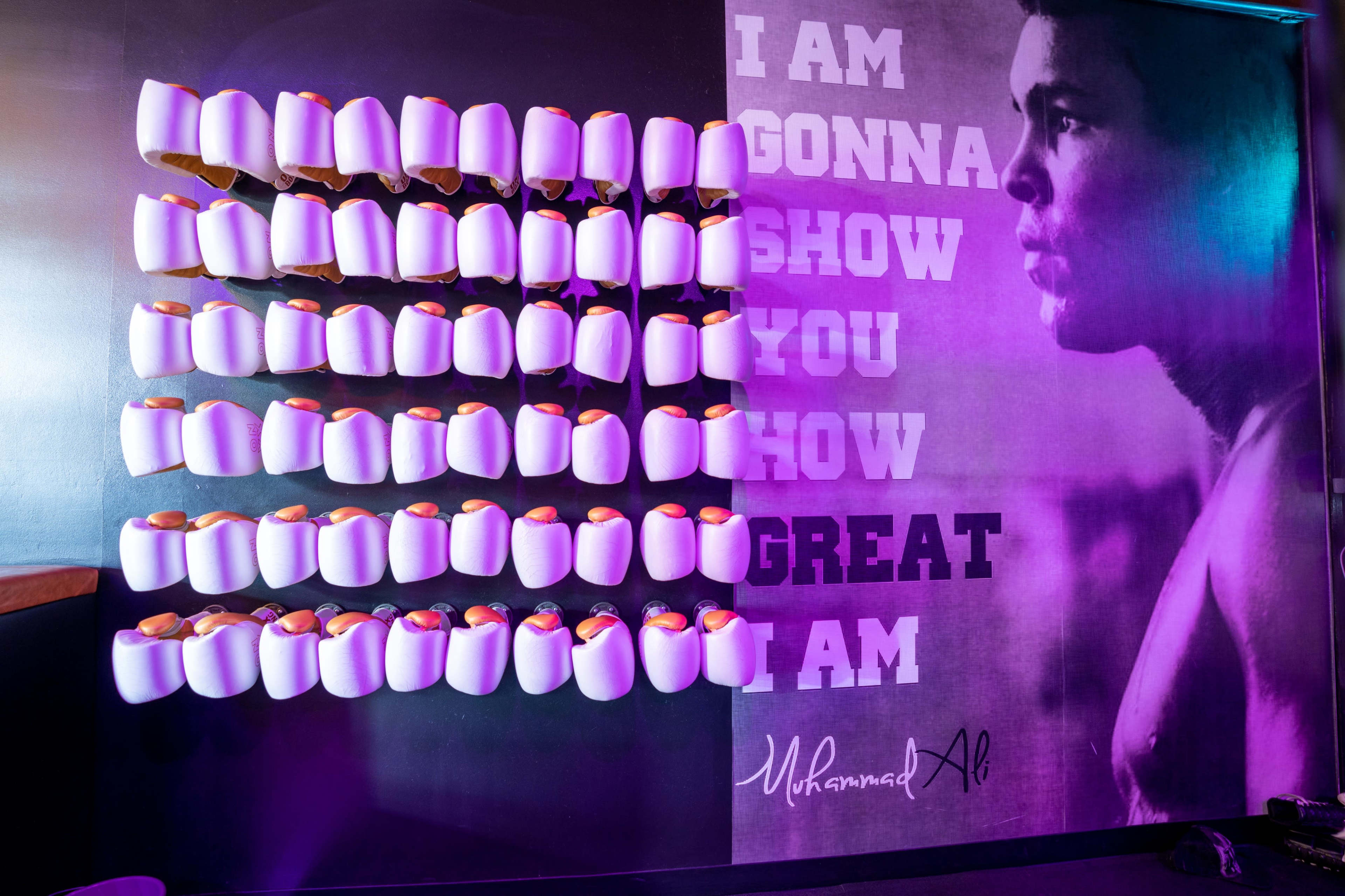 A wall display with white items arranged in rows alongside a large portrait of Muhammad Ali and a motivational quote attributed to him.