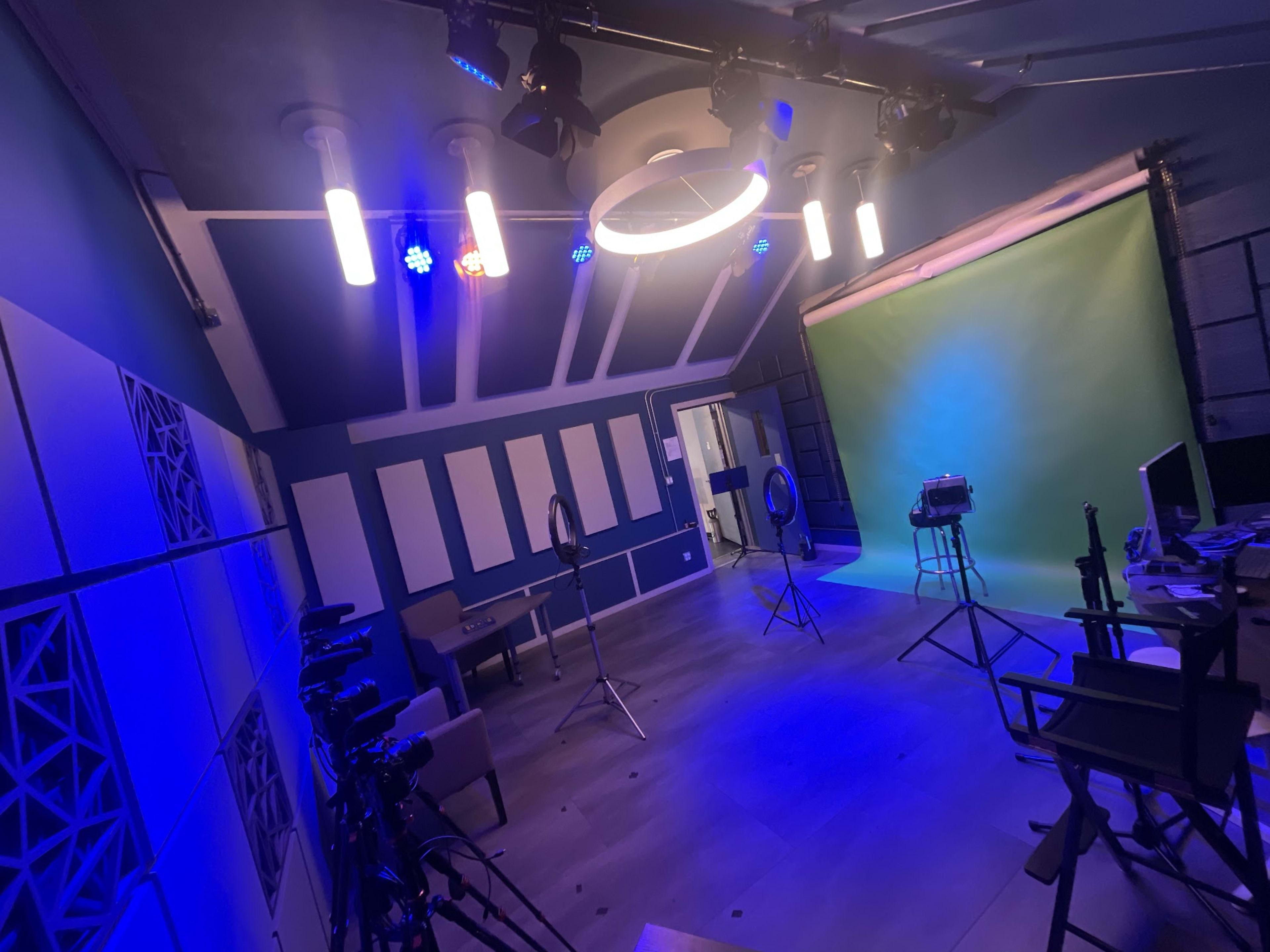 A video recording studio featuring green and blue backdrops, lighting equipment, and camera stands.