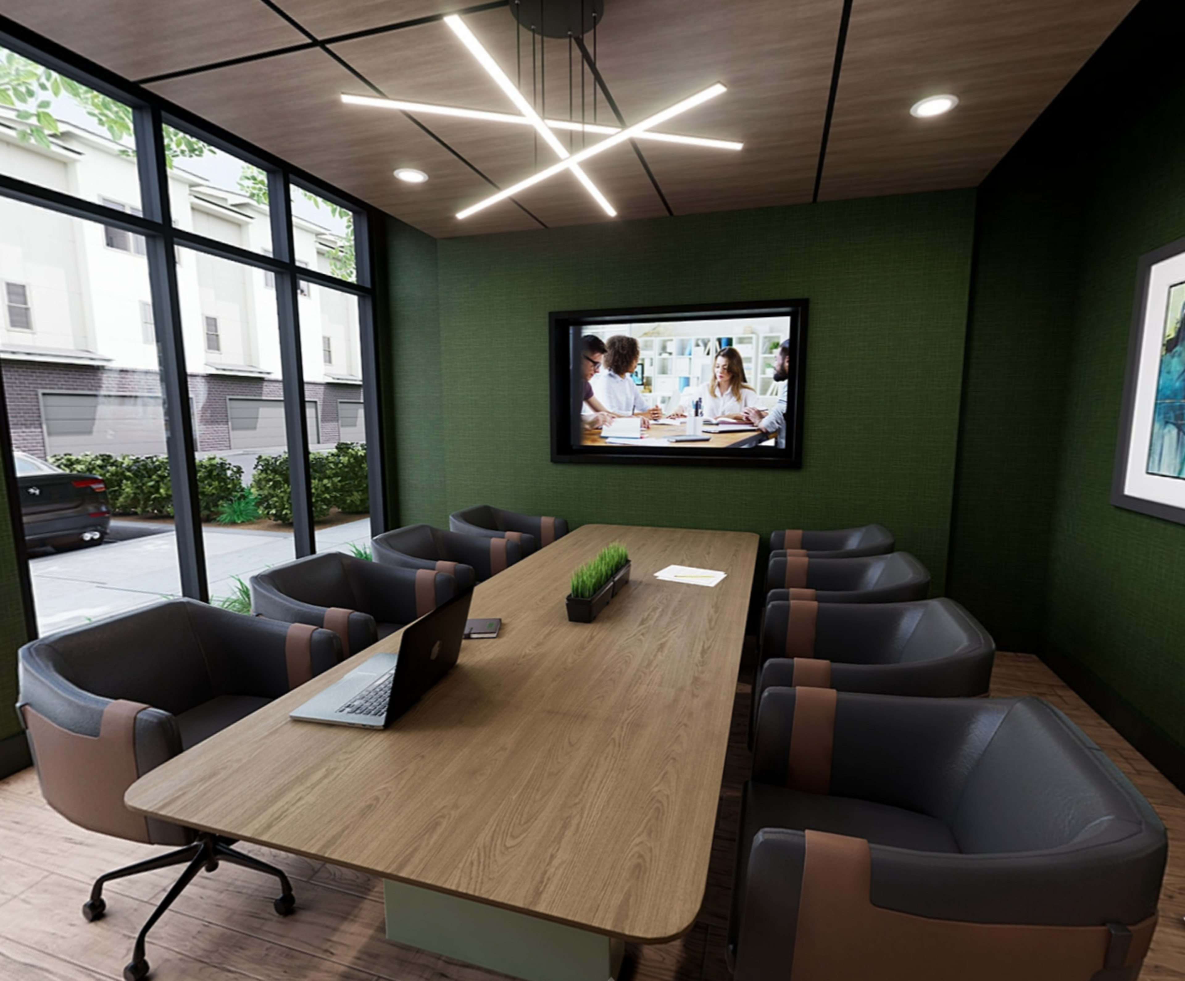 A modern conference room features a large wooden table, gray chairs, a laptop, and a TV displaying a group of people in a meeting, with large windows providing a view of the exterior.