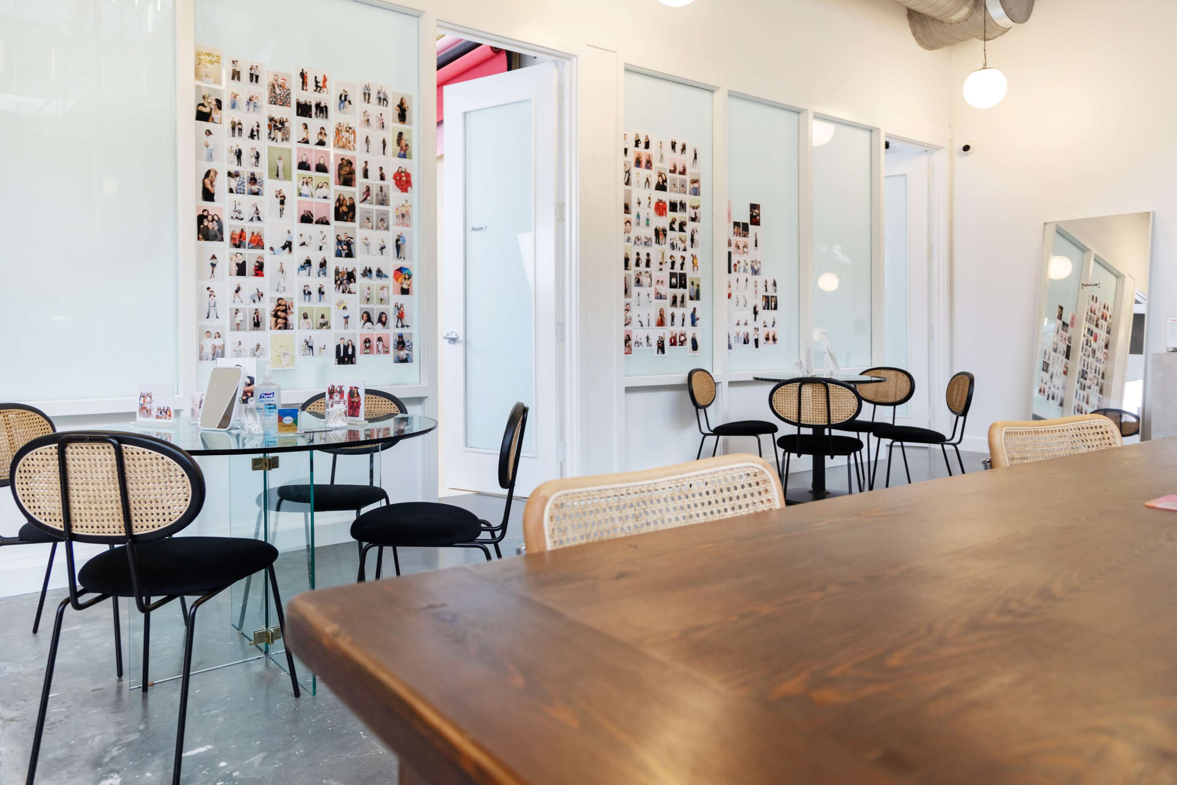 A cafe-like interior featuring several tables, sleek chairs, and walls adorned with a collage of photos.