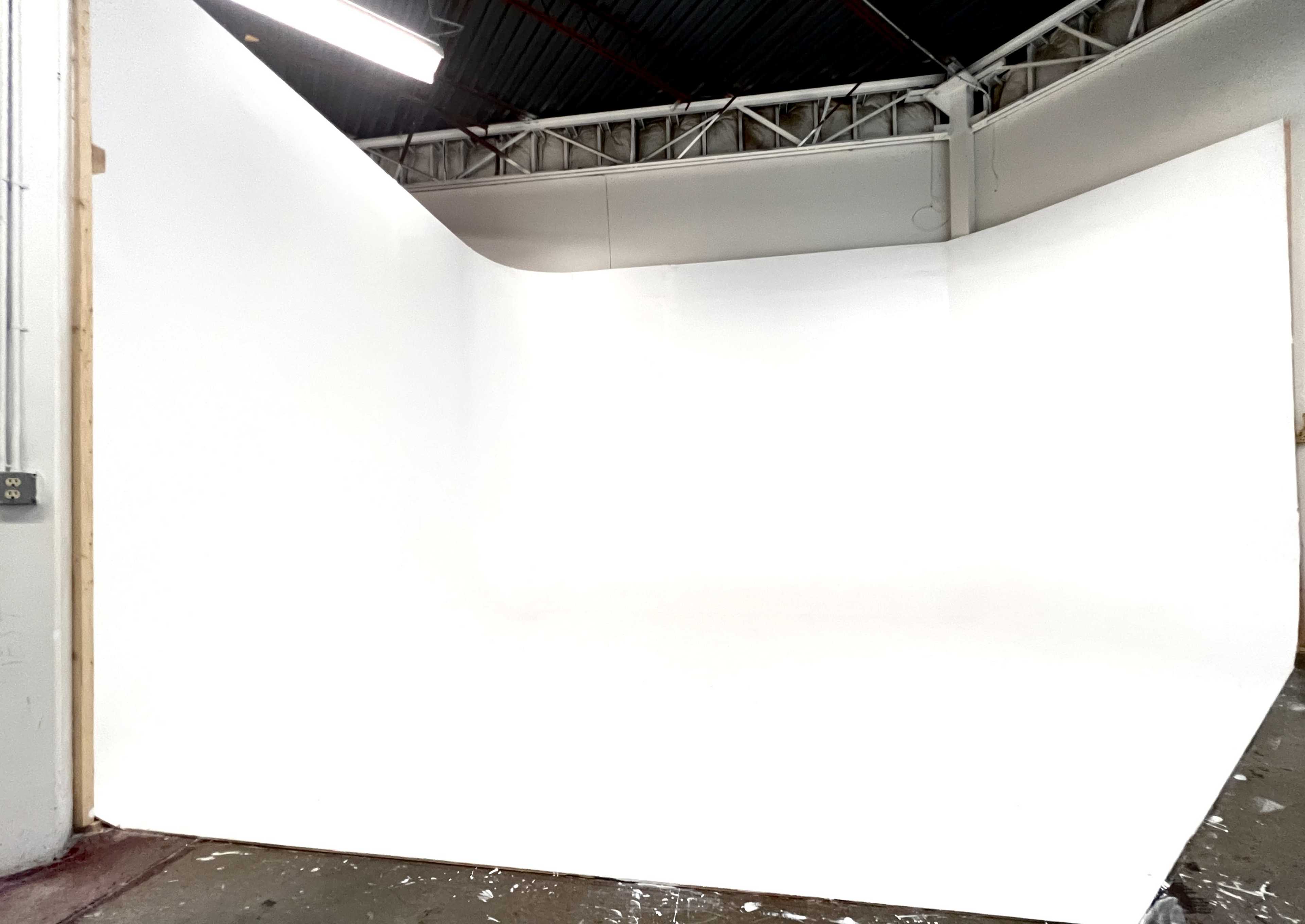 A spacious studio with a large white backdrop and an empty floor.