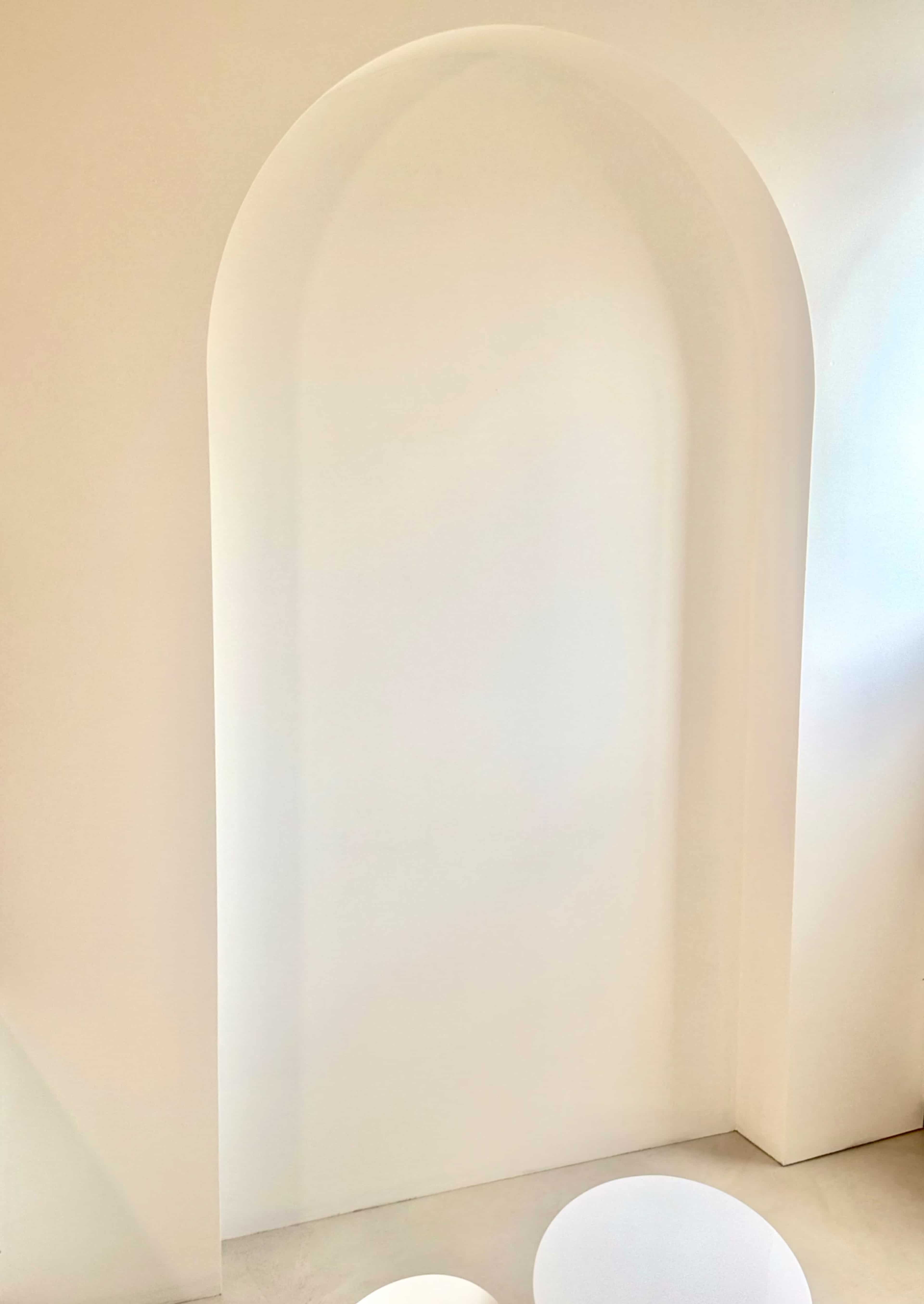 The image shows a curved archway set into a white wall.