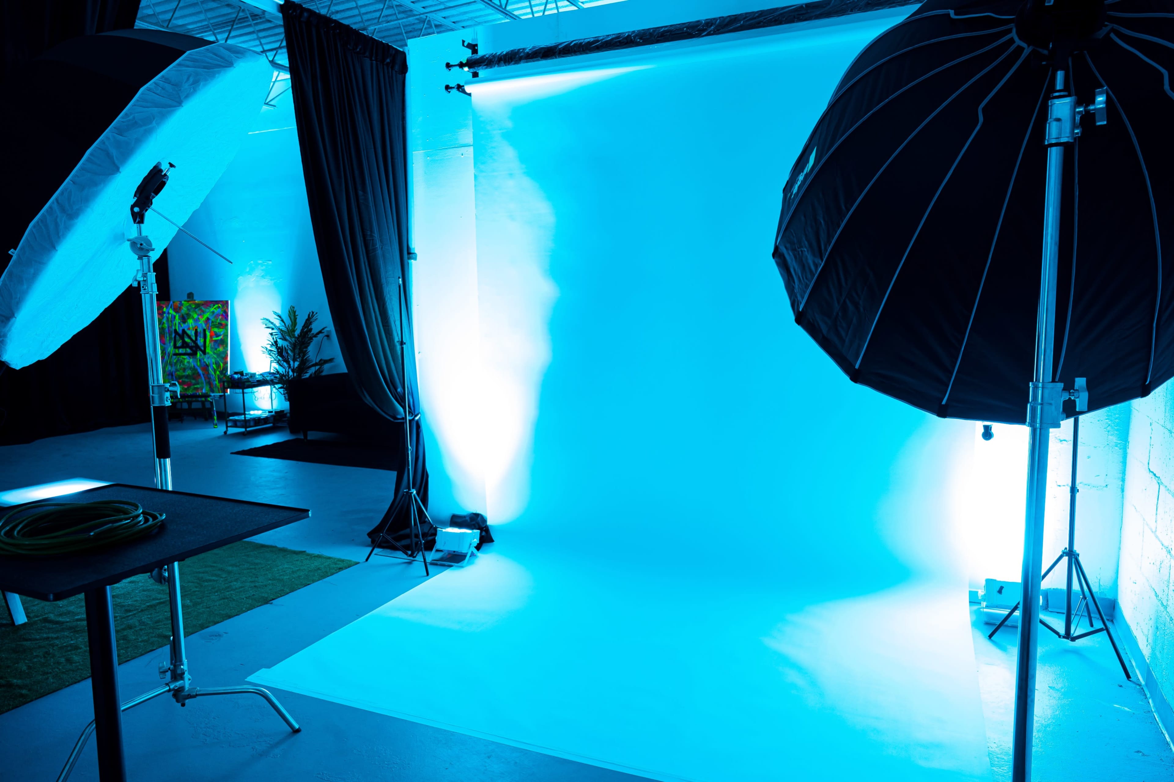 A photography studio setup with an illuminated blue backdrop and two large softbox lights on either side.