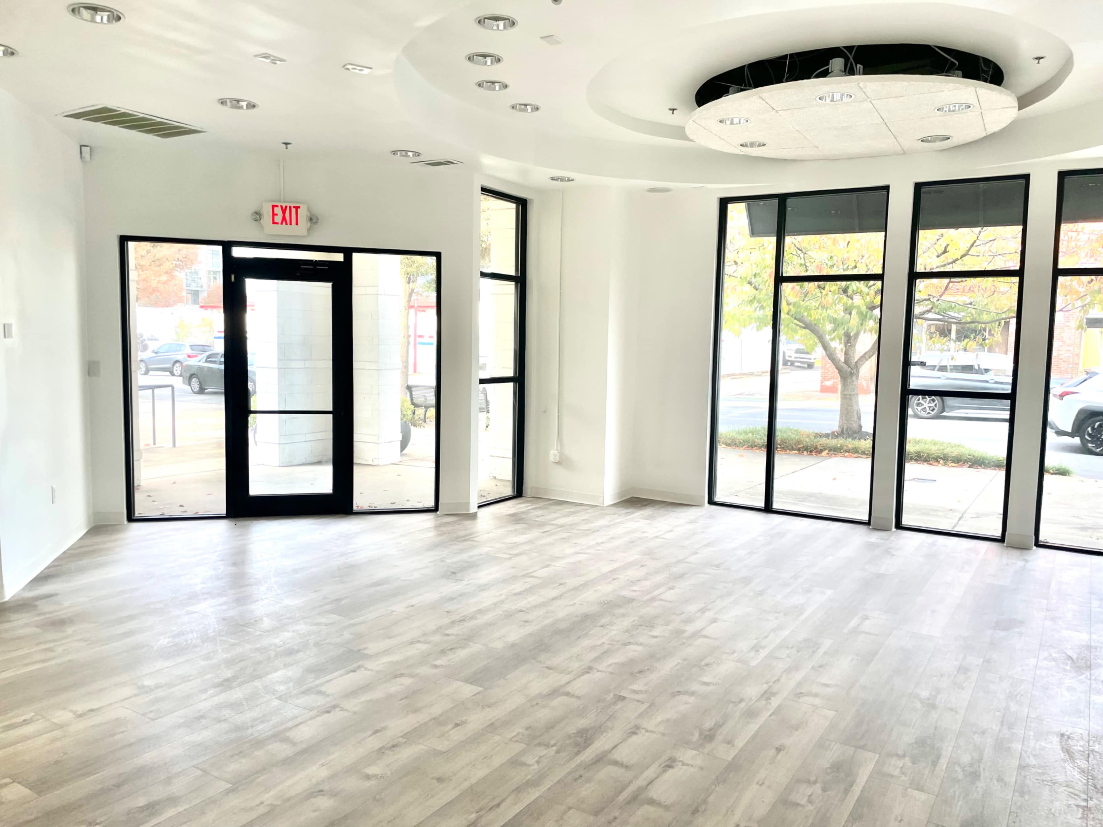 A vacant commercial space with large windows and a modern ceiling design.