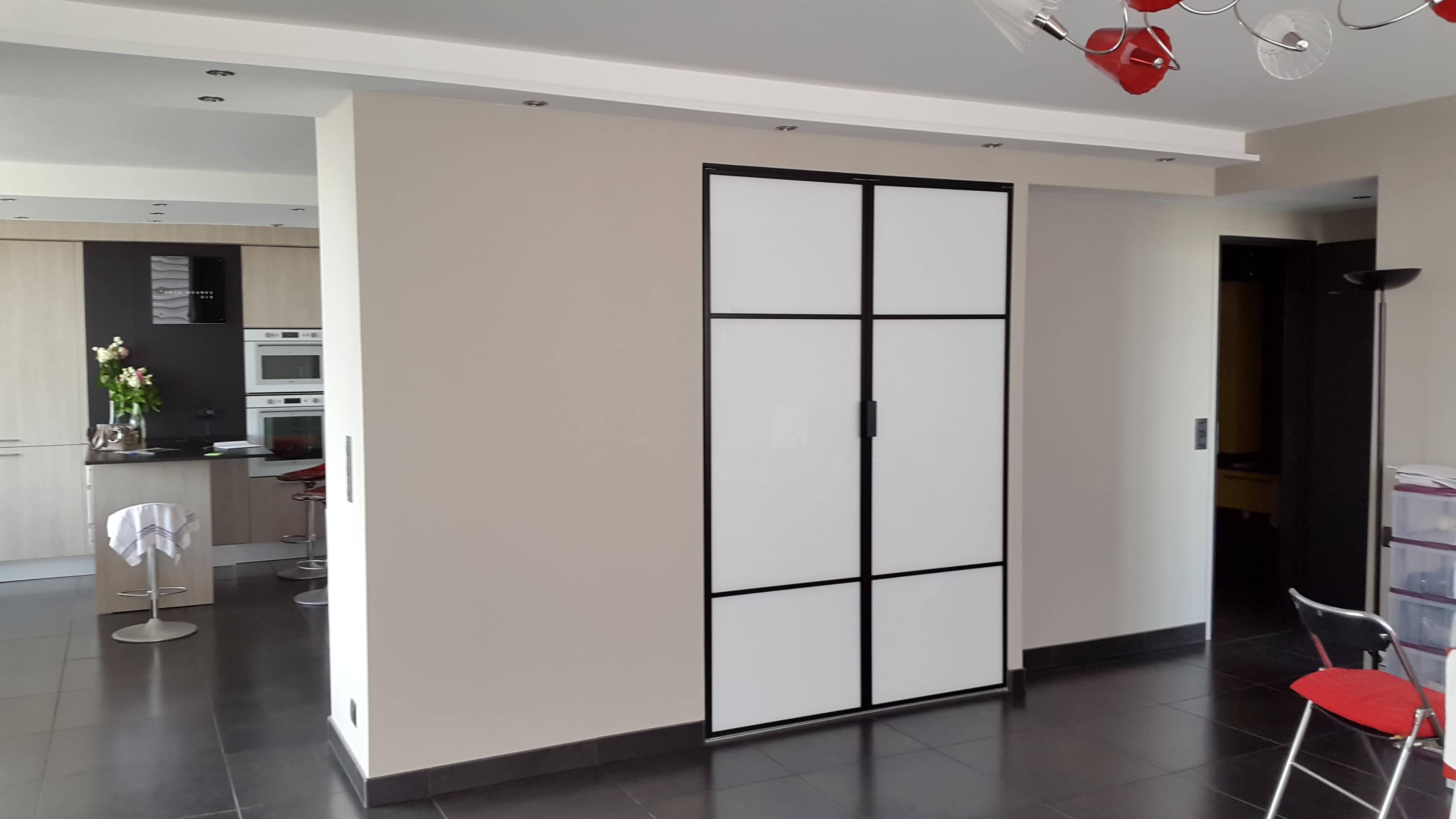 A modern open-plan living space with a sliding panel door separating the kitchen area from the rest of the room.