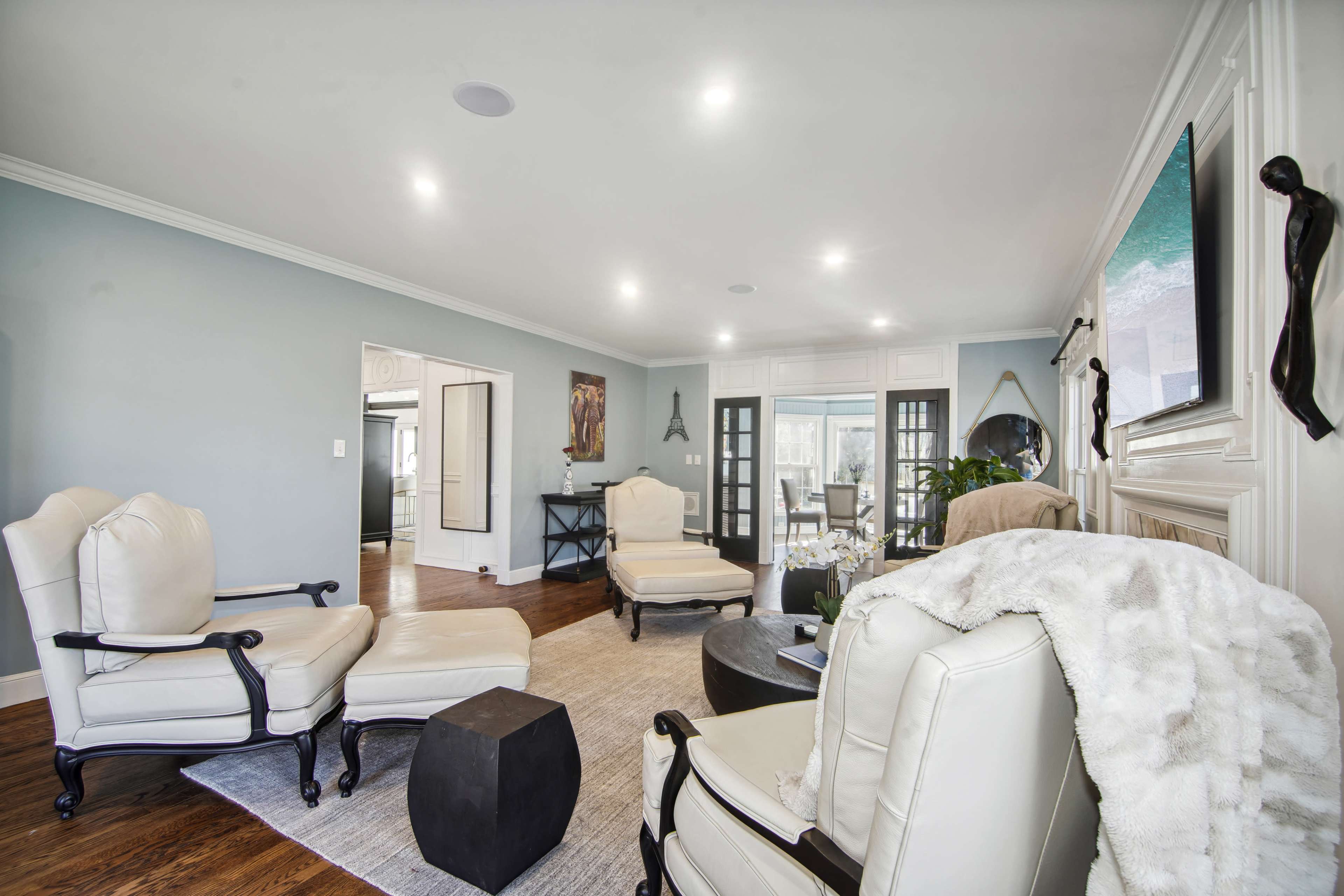A modern living room with two white armchairs, a black coffee table, and a doorway leading to another room.