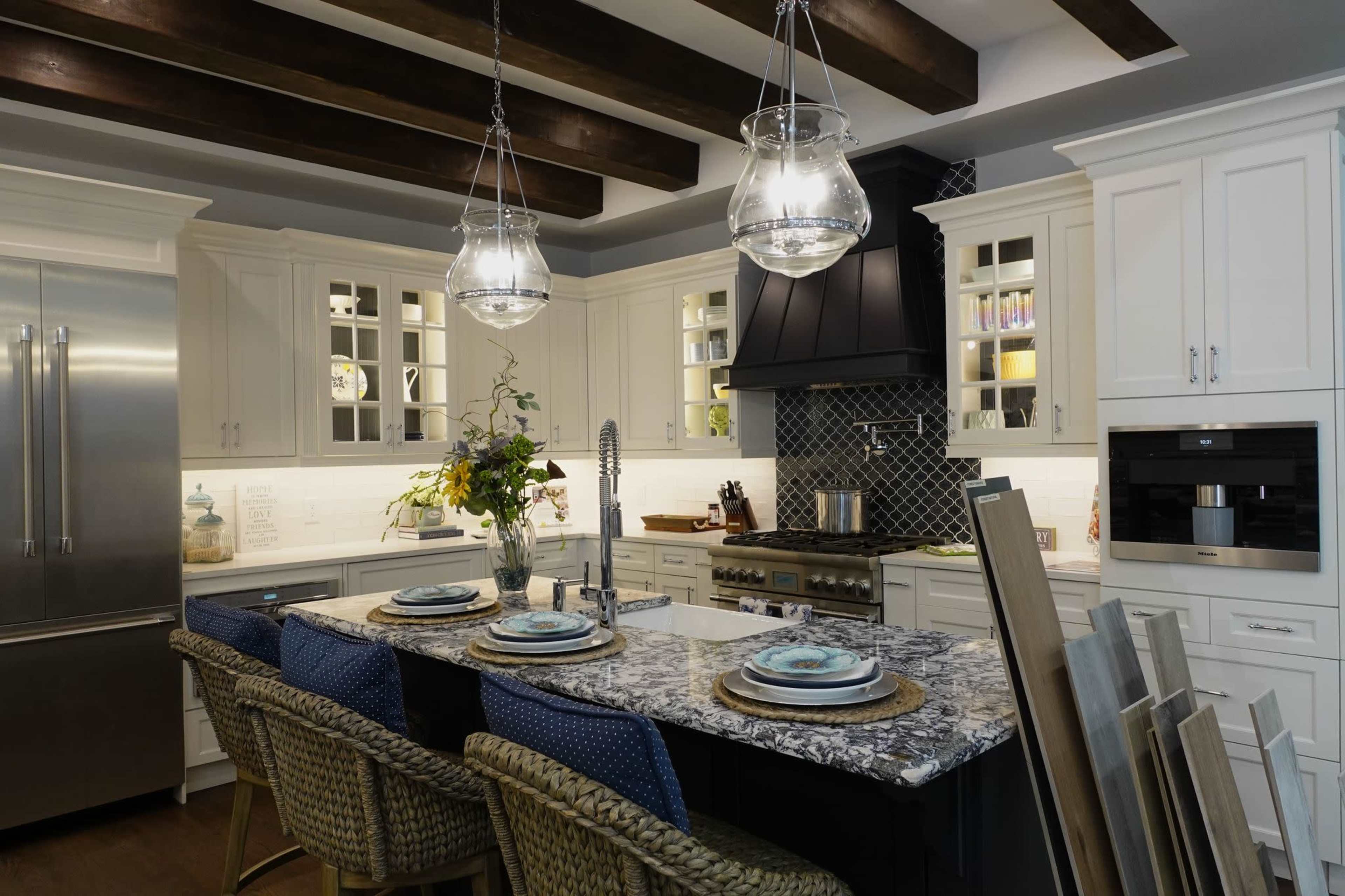A modern kitchen with white cabinetry, a central island with a patterned countertop, and pendant lighting above.