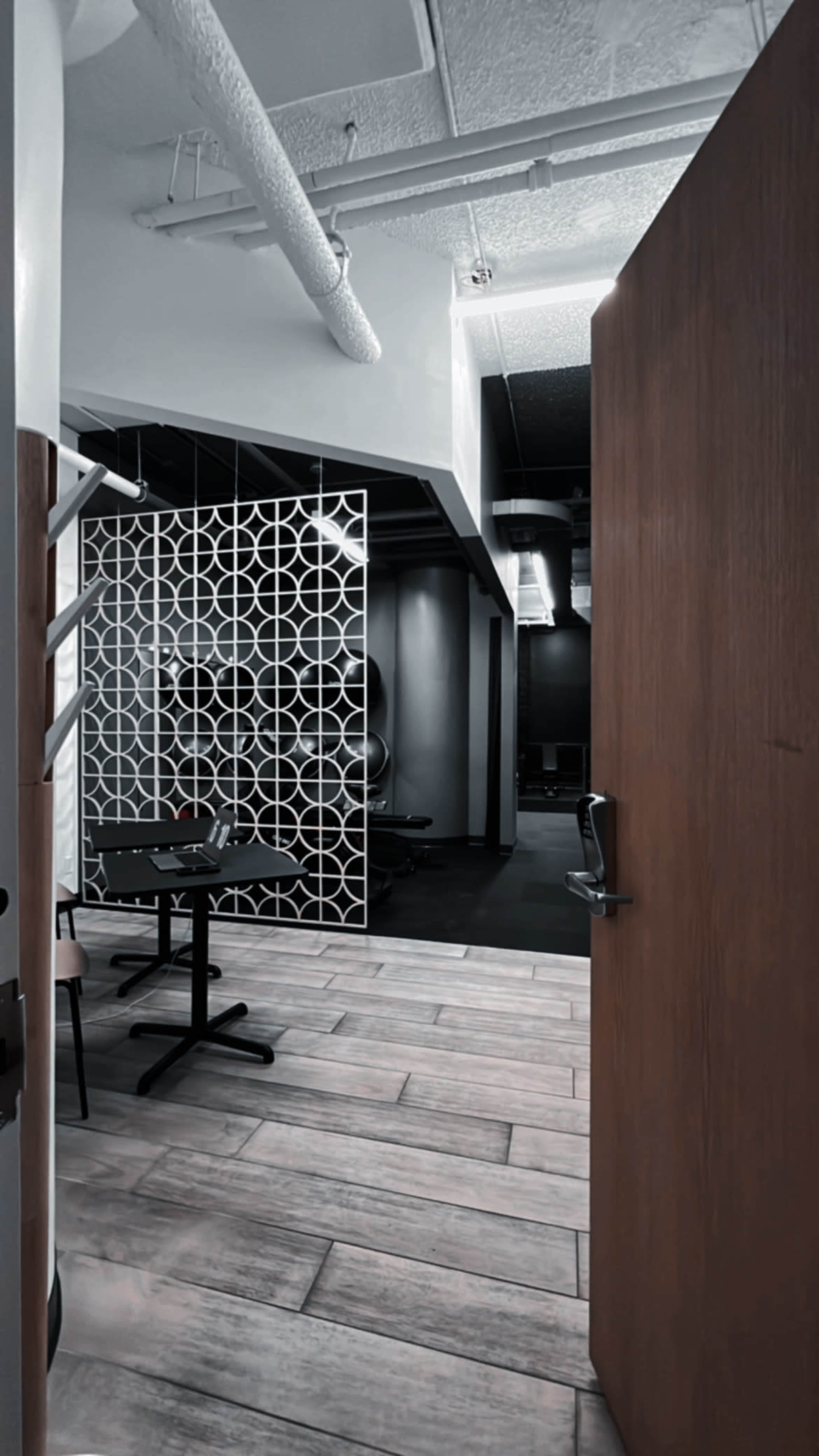 An open door leading into a modern office space with a table and chairs, and a decorative partition in the background.