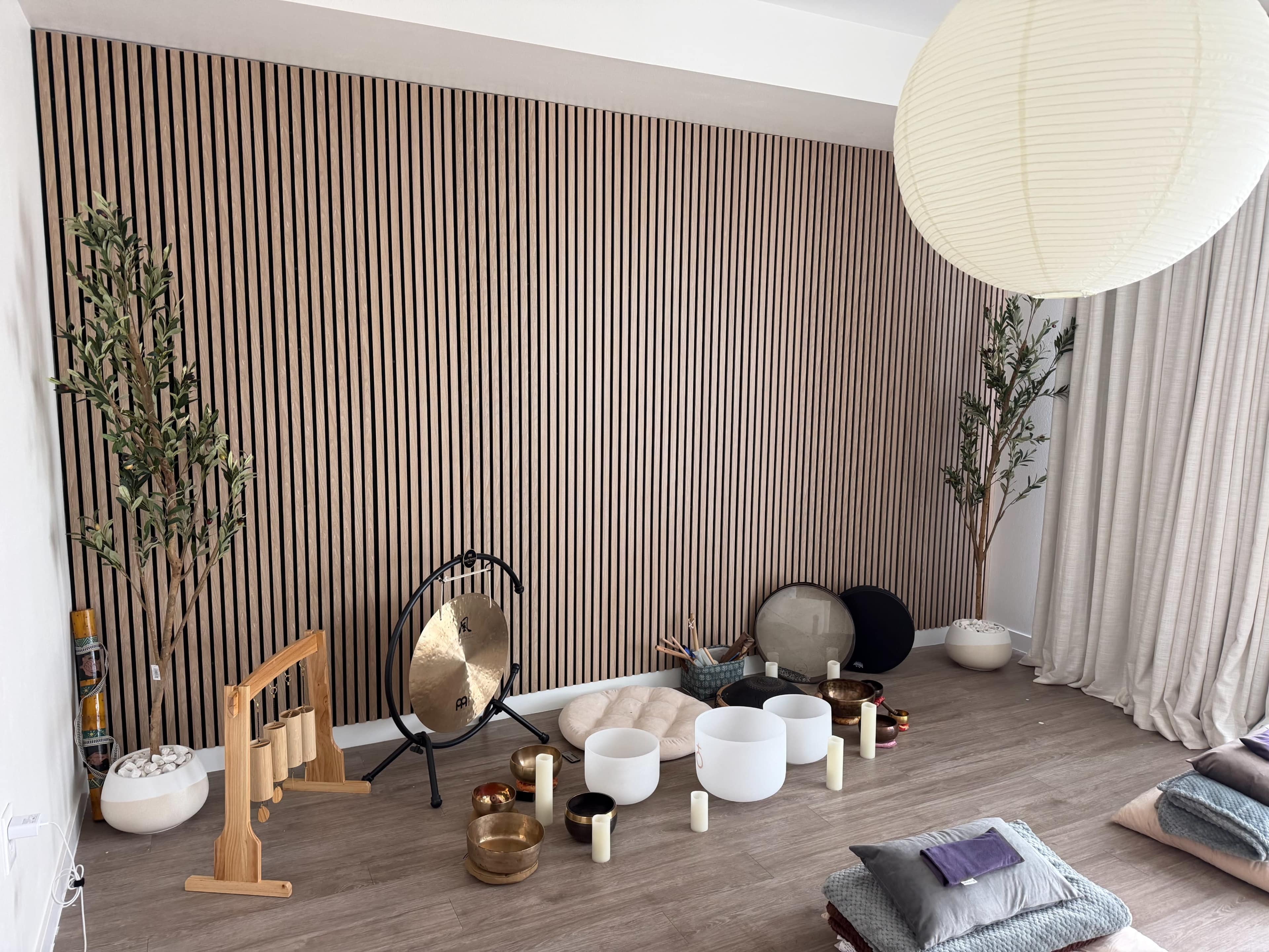 The image shows a serene room with wooden slat walls, various decorative items, and soft seating arrangements.