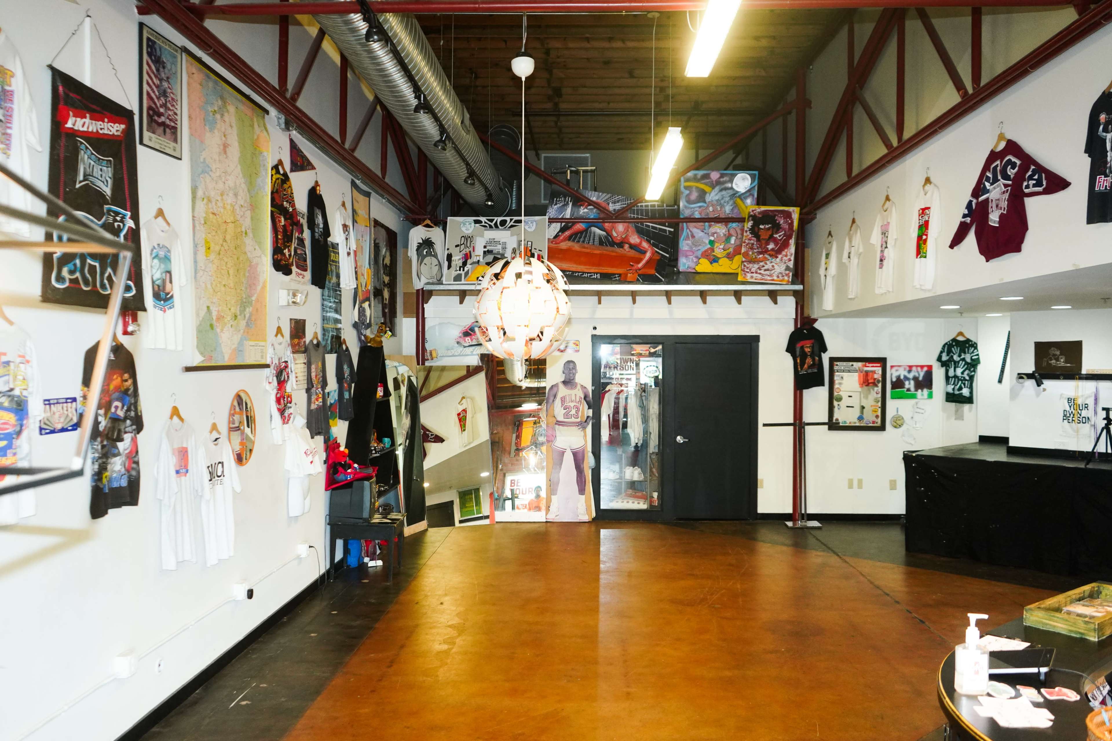 An interior space featuring a mix of clothing displays, wall art, and a staircase leading to the upper level.