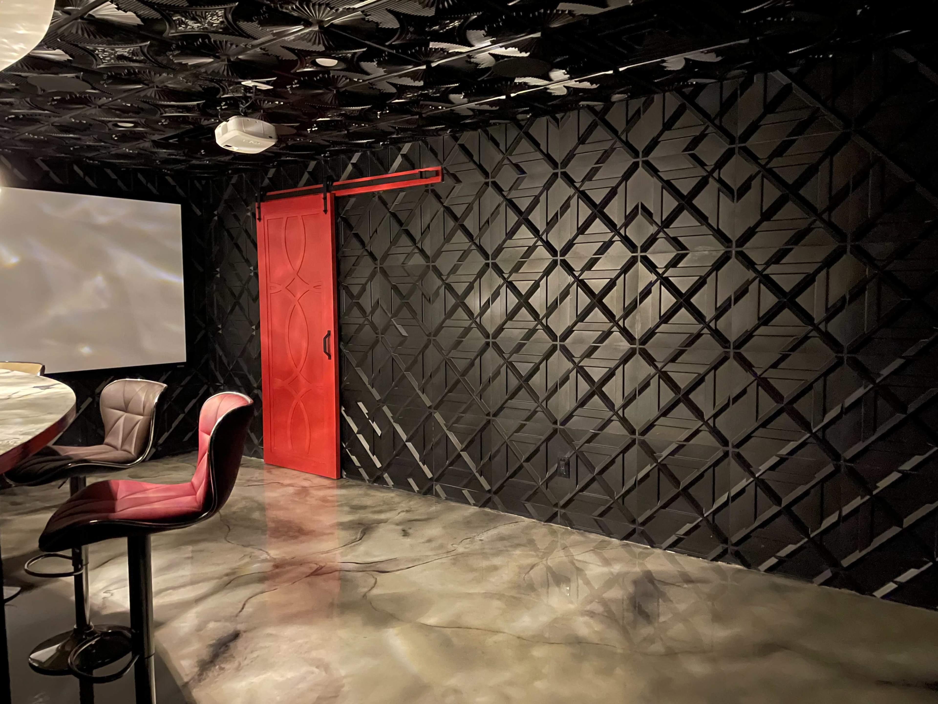 The image shows a modern meeting room with a textured black wall, a red sliding door, and a glossy concrete floor.