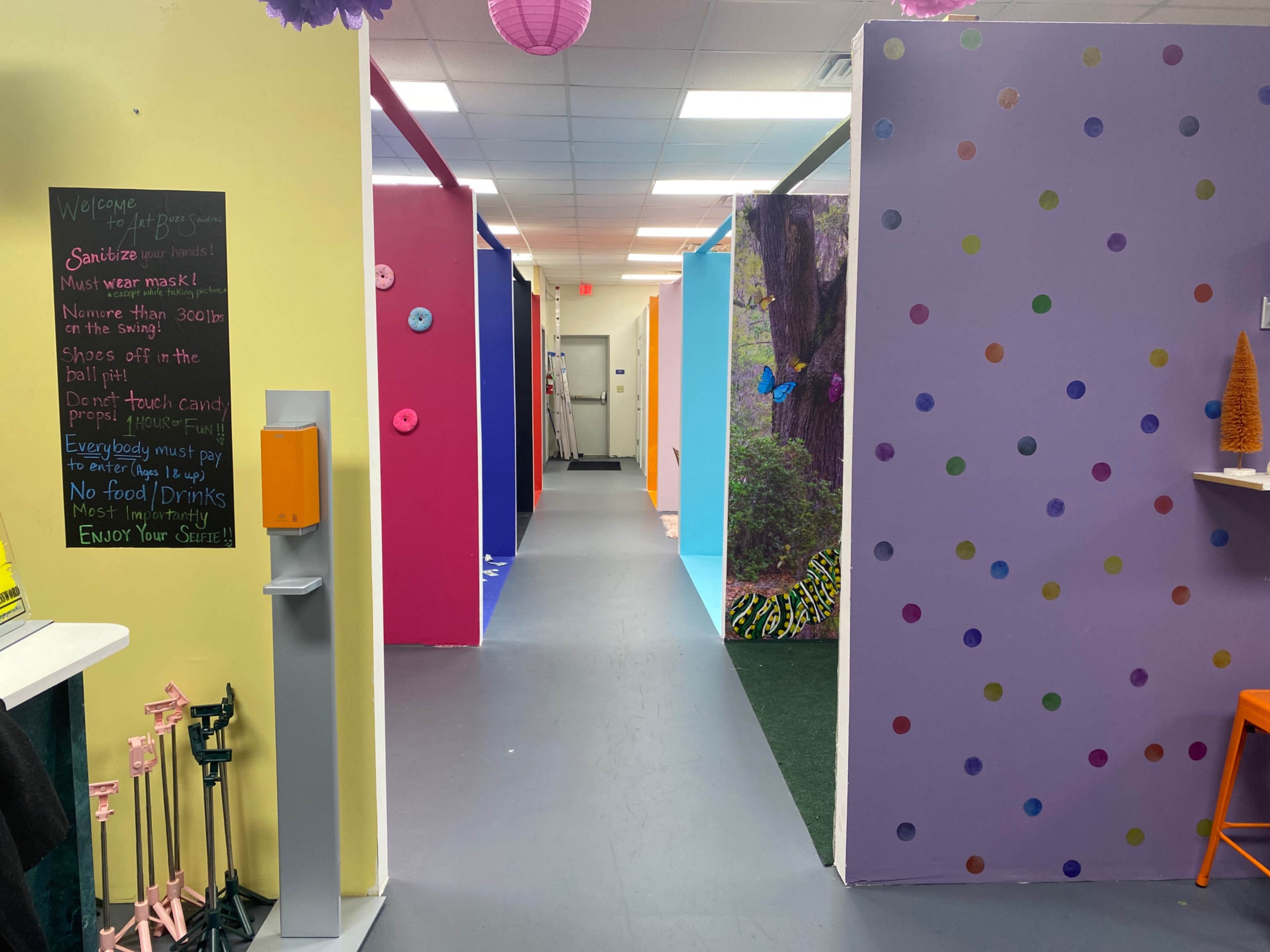 The image shows a brightly colored hallway with walls painted in various pastel shades and playful polka dots, leading to different rooms.