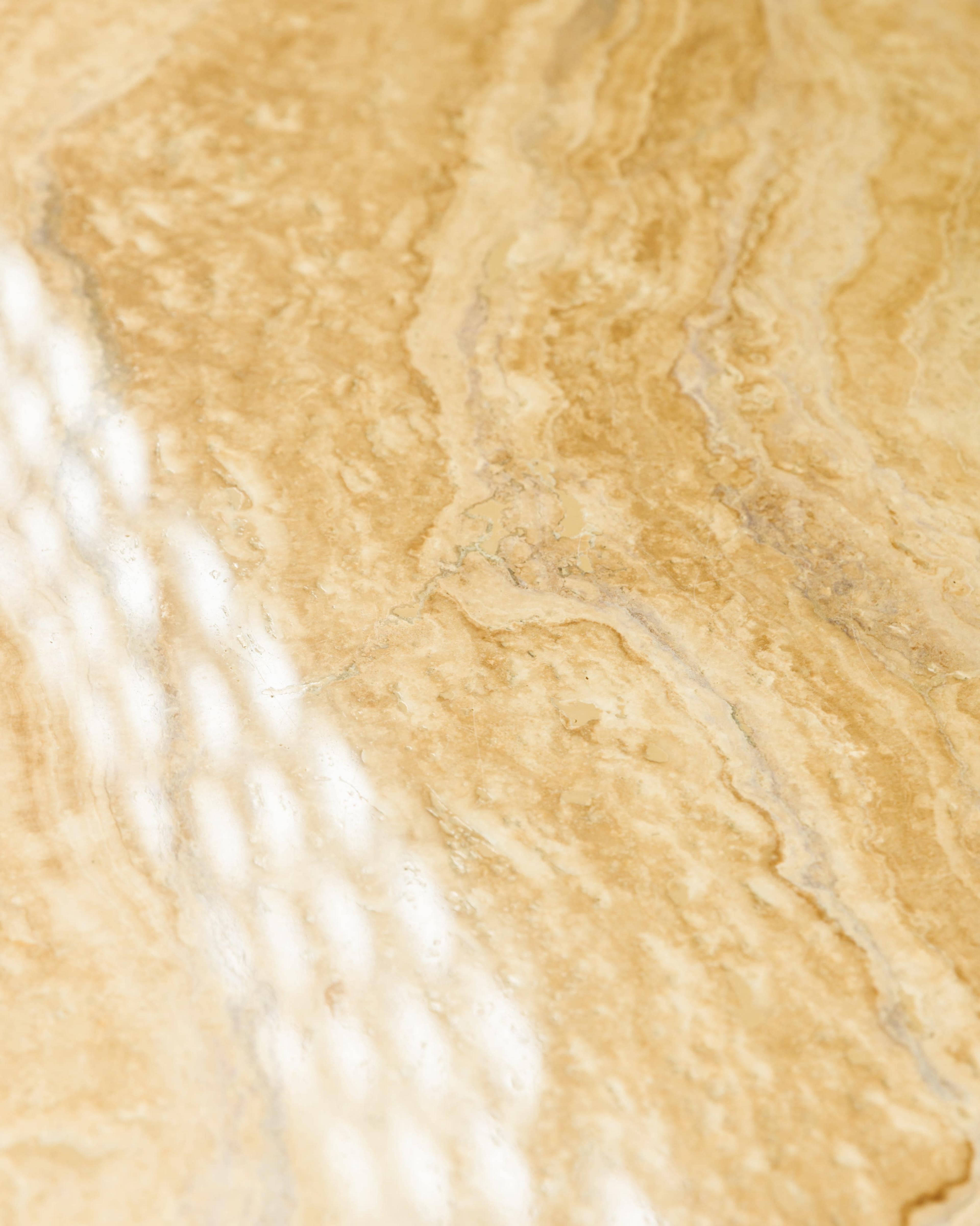 A close-up view of a polished marble surface with beige and gold veins.