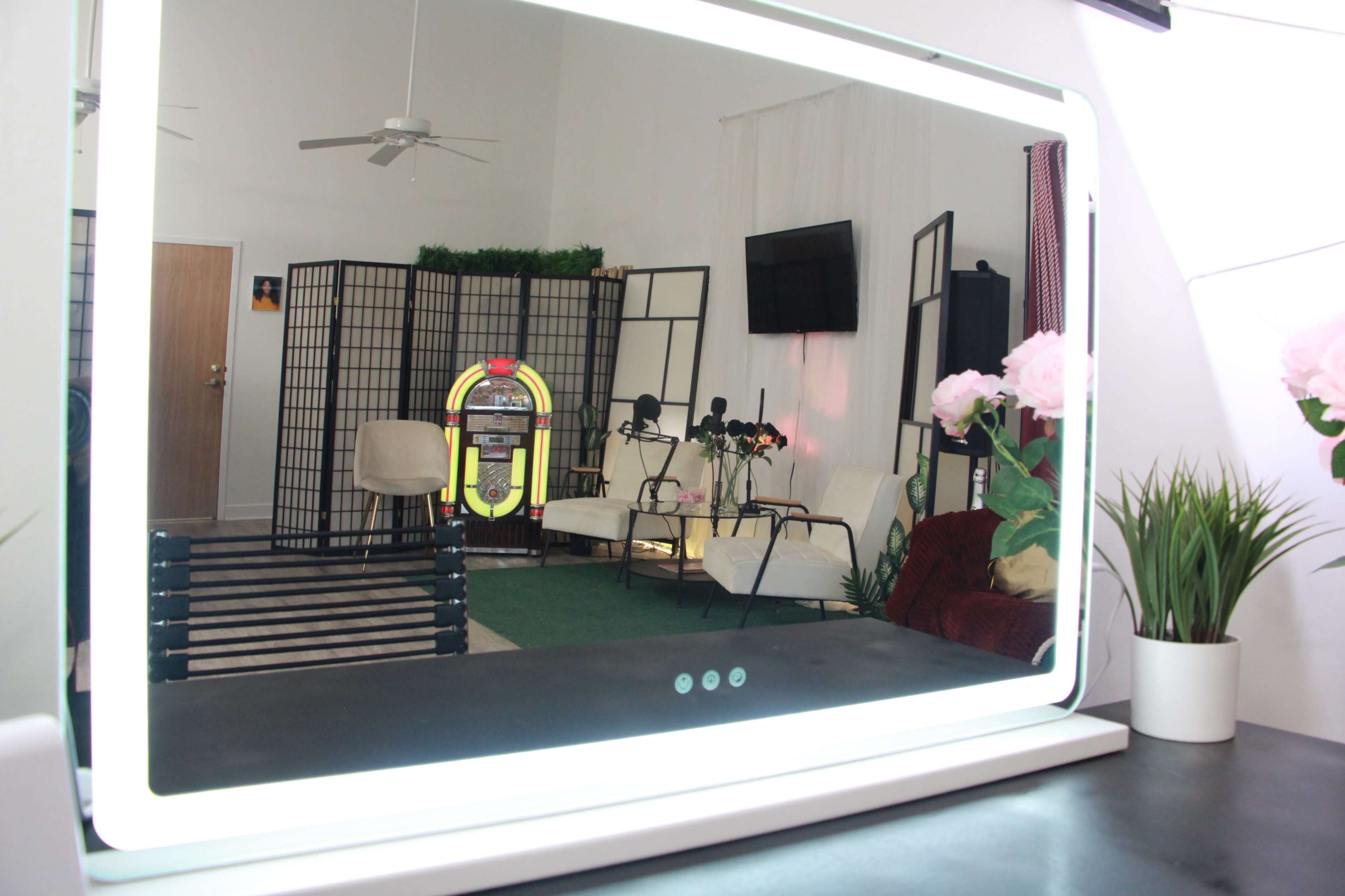 The image shows a brightly lit room with a mirror in the foreground, featuring a seating area and a jukebox in the background.