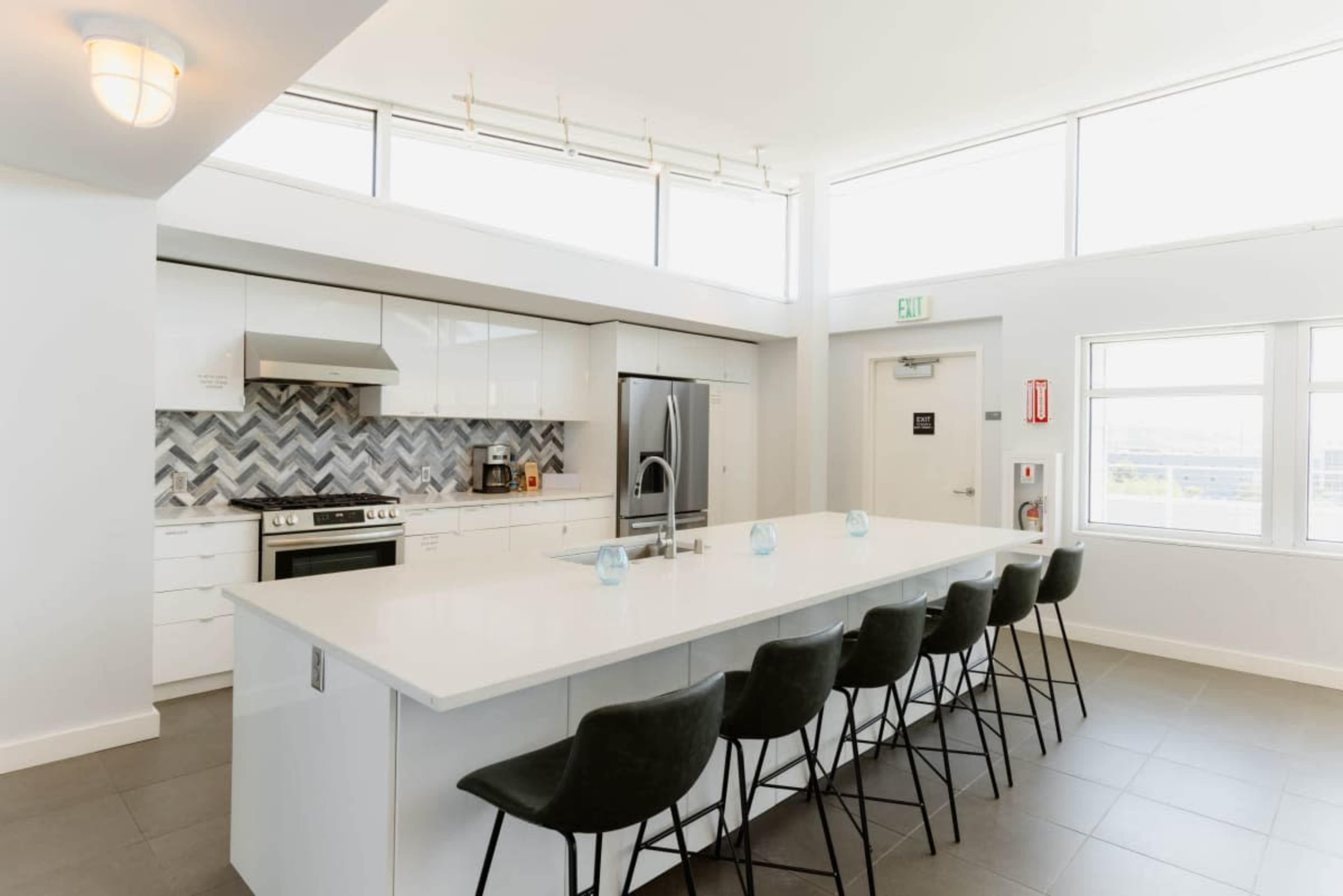 The modern kitchen features a large island with seating, a sleek design, and ample natural light from the surrounding windows.