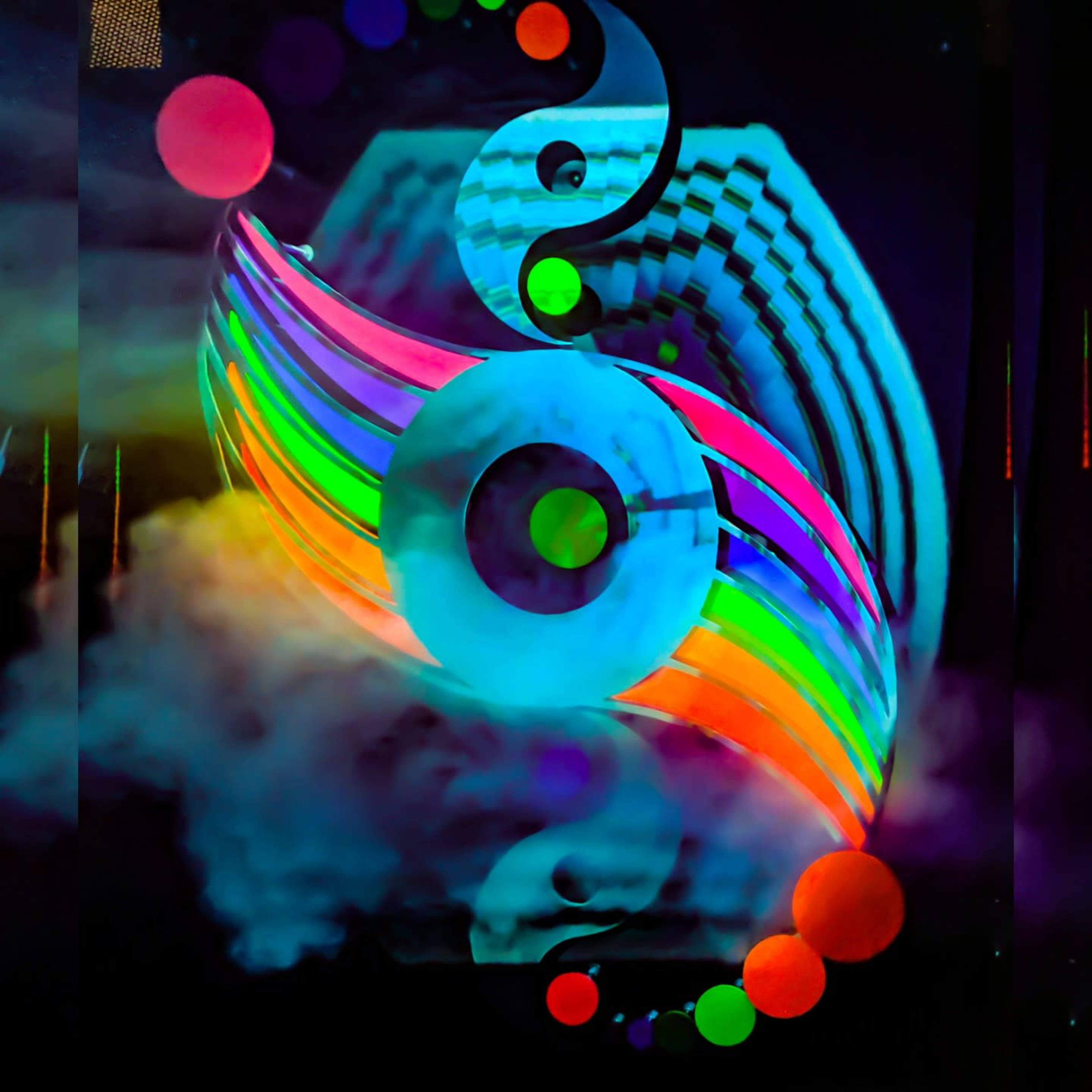 Vibrant, swirling patterns of light in various colors against a dark background, with circular and spherical shapes partially shrouded in mist.