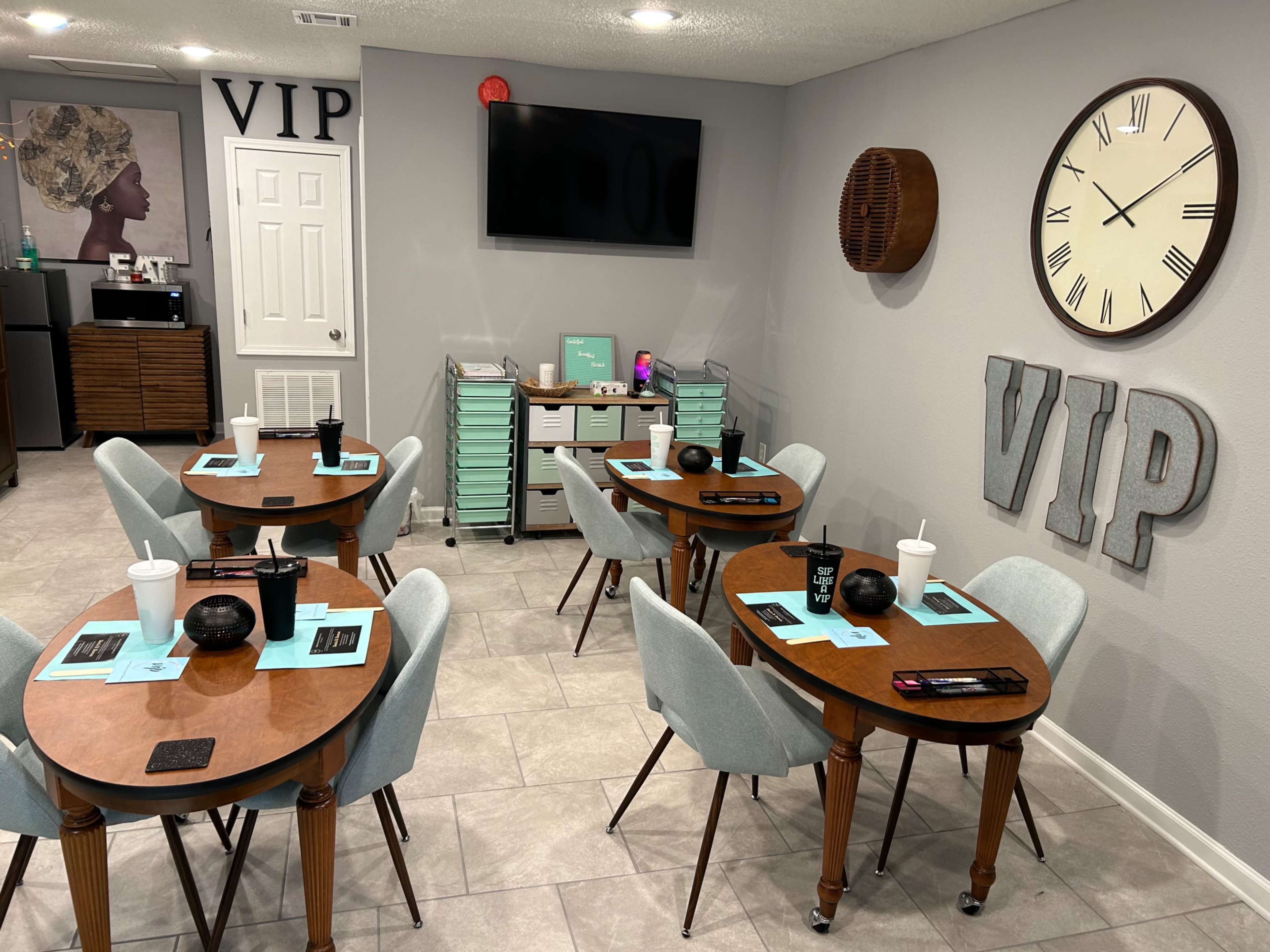 A small dining area with four wooden tables set for a meal, a clock on the wall, and the letters "VIP" displayed prominently.