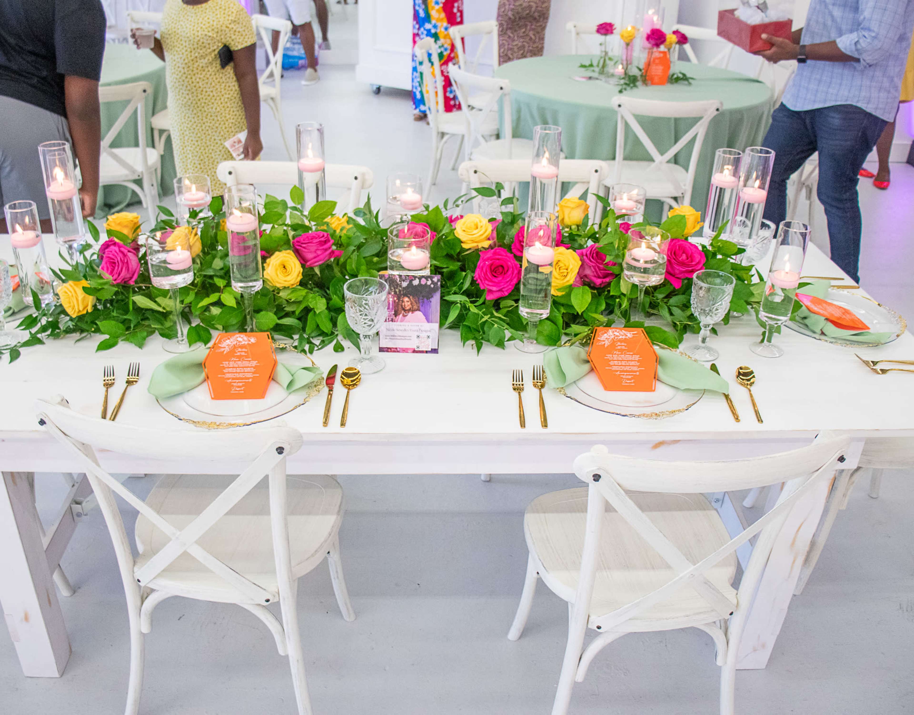 A beautifully arranged dining table features vibrant floral centerpieces, elegant tableware, and decorative candles.