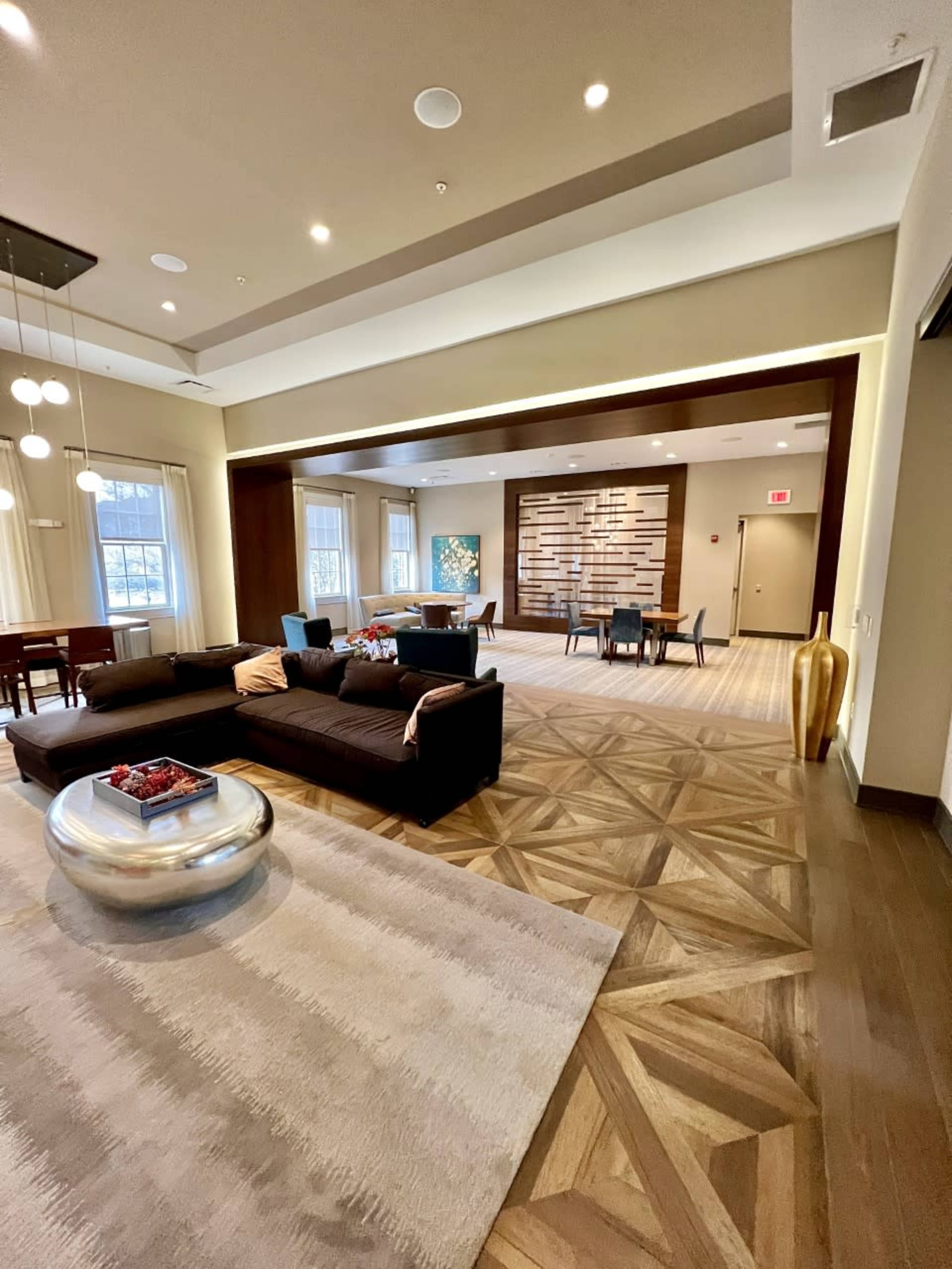 A spacious interior lounge area with contemporary furniture, a large round table, and a decorative accent wall made of wood.