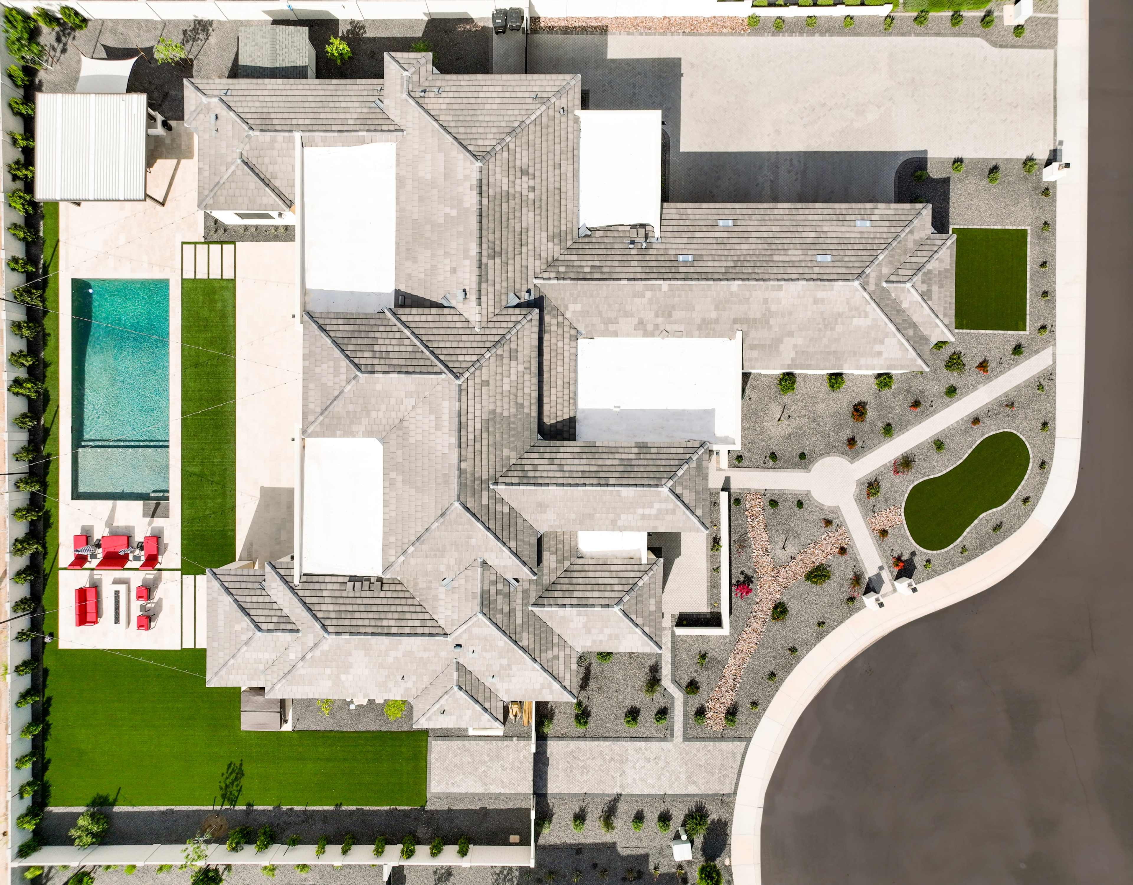 An aerial view of a large property featuring a main house, a swimming pool, manicured lawns, and landscaped pathways.