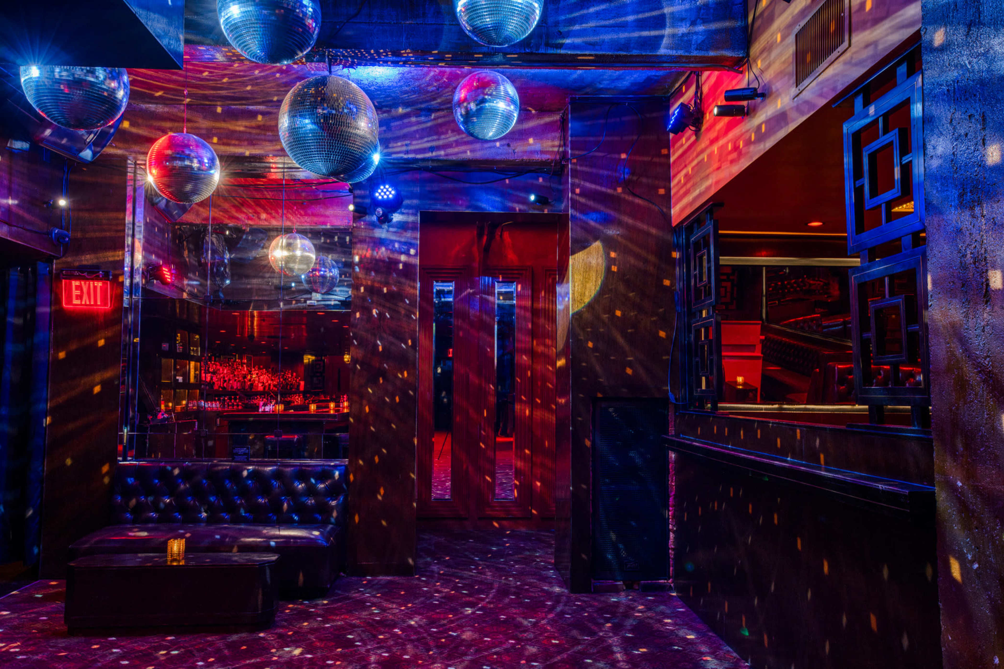 The image shows an illuminated lounge area with disco balls reflecting colorful lights onto the walls and floor.