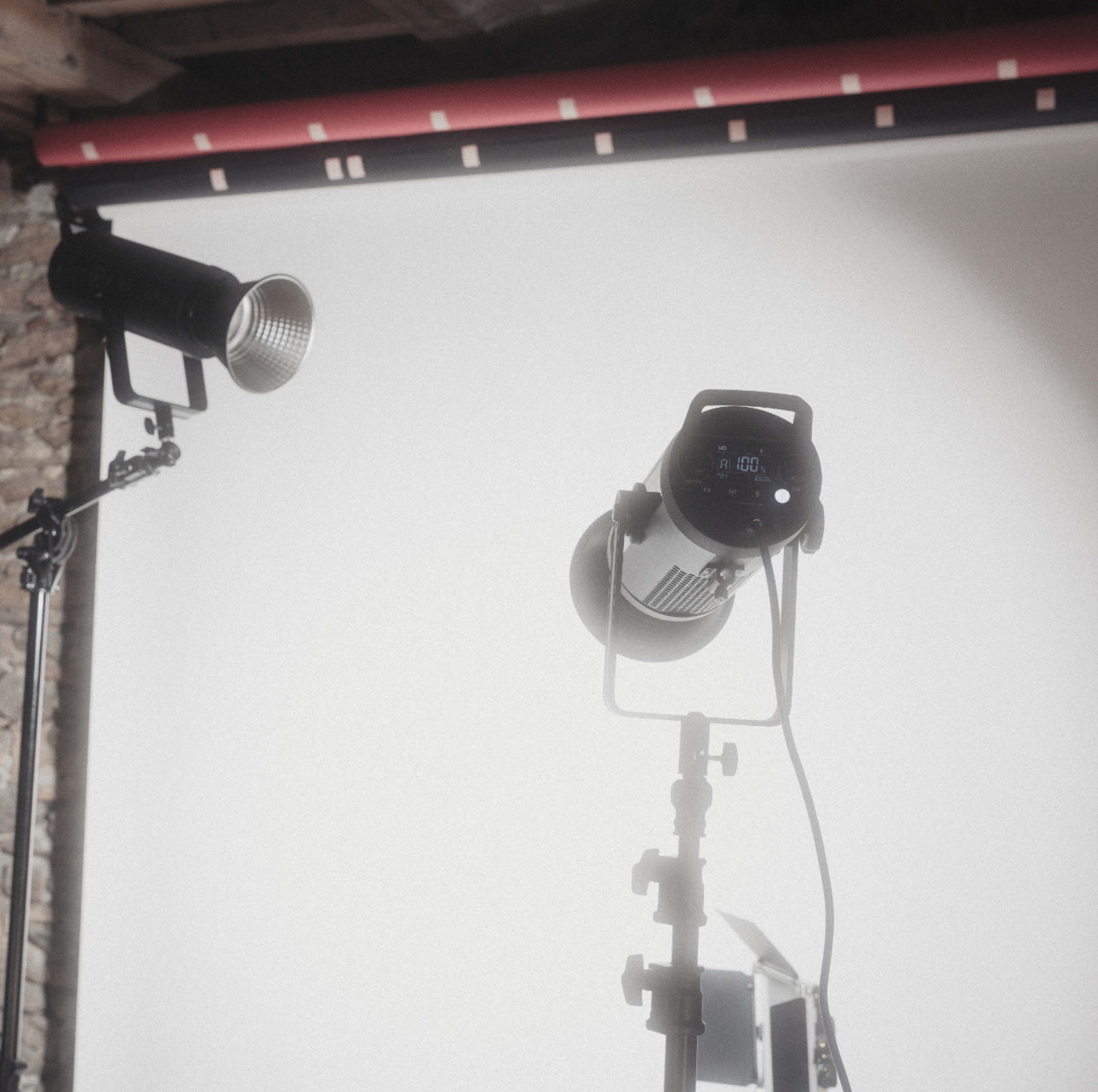 The image features two studio lights positioned in front of a plain backdrop.