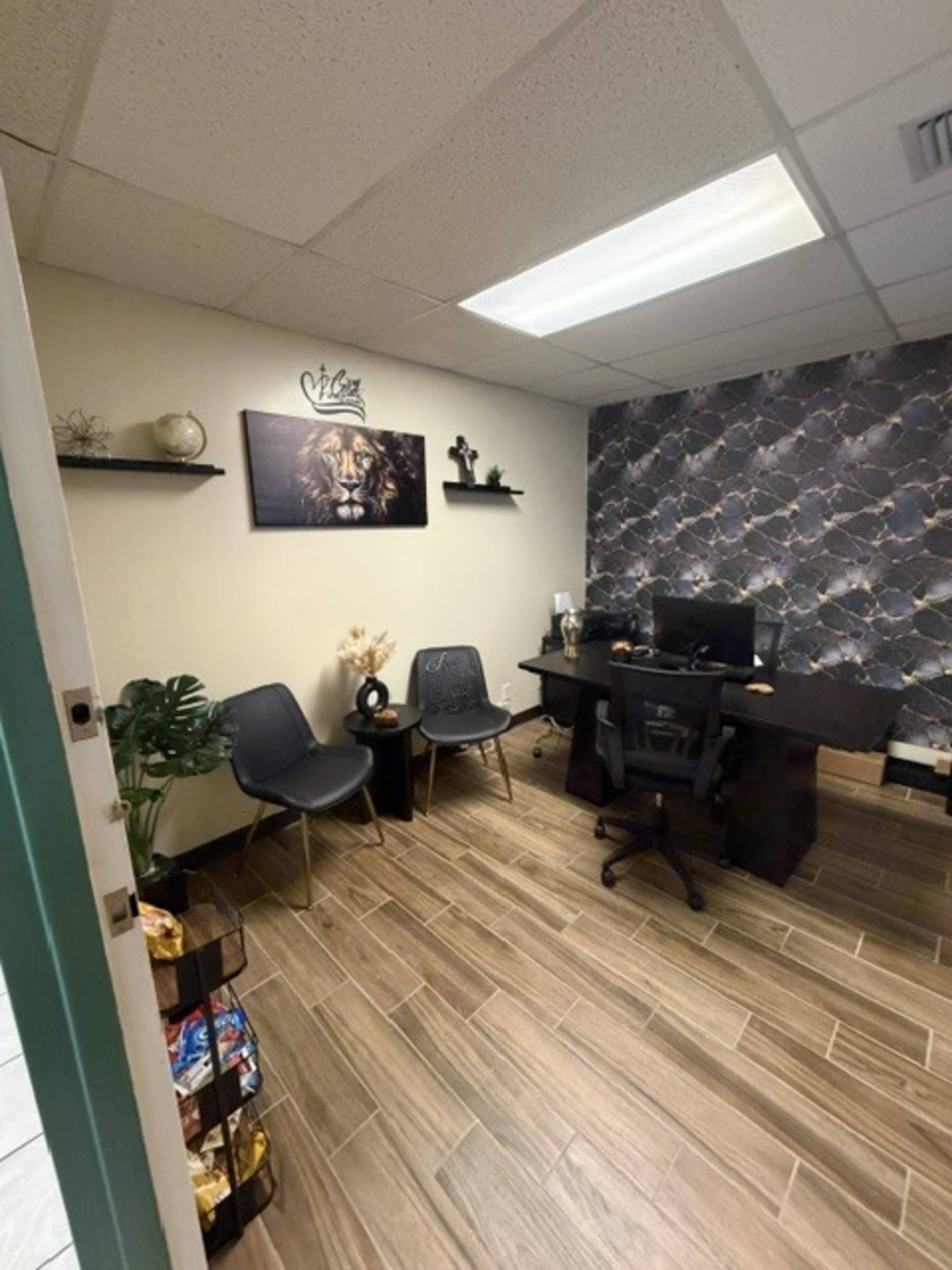 The image shows a well-arranged office space featuring a black desk, two gray chairs, and a decorative wall with patterned wallpaper.