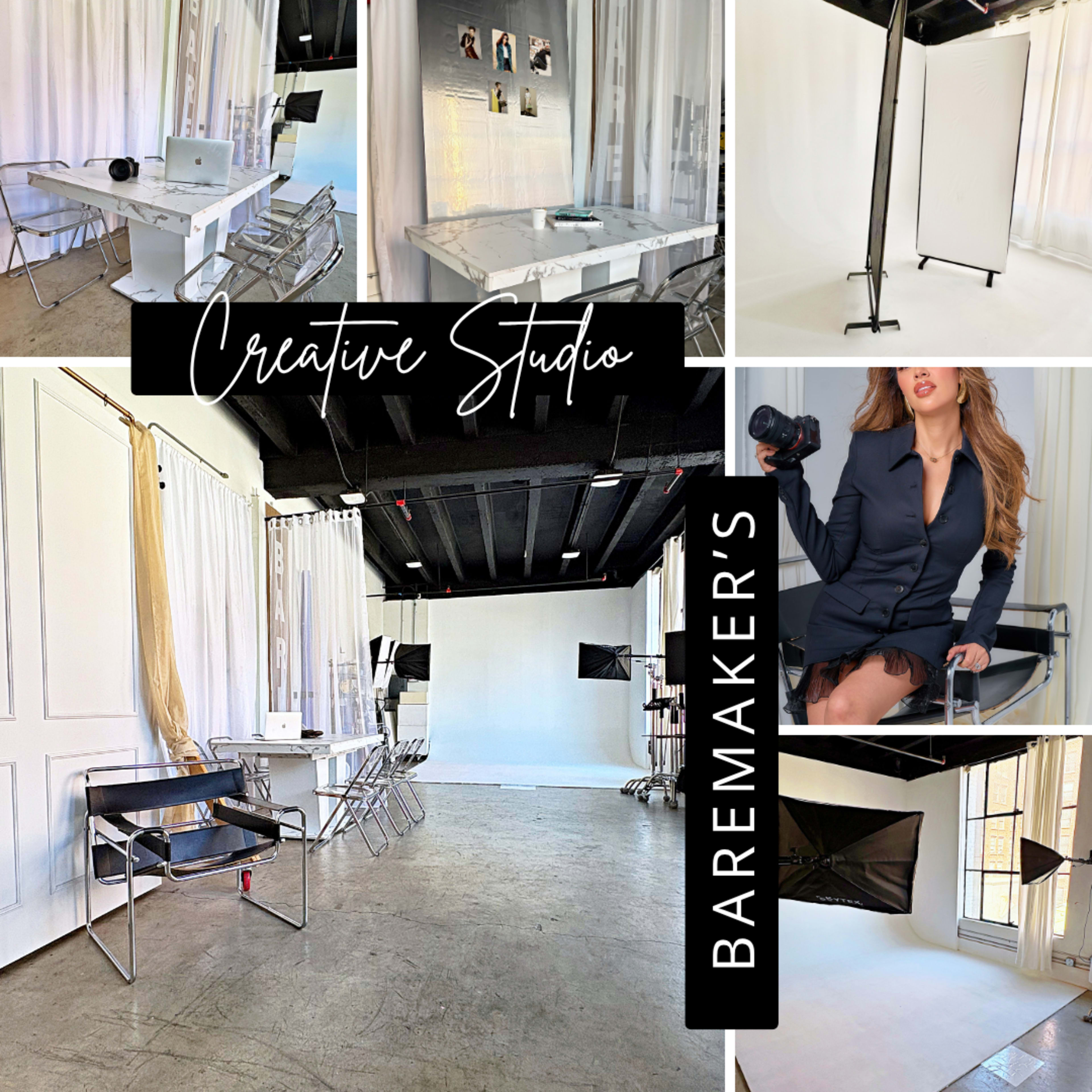 The image shows a bright, minimalist creative studio featuring a variety of workspaces, including a desk, seating area, and backdrop for photography.