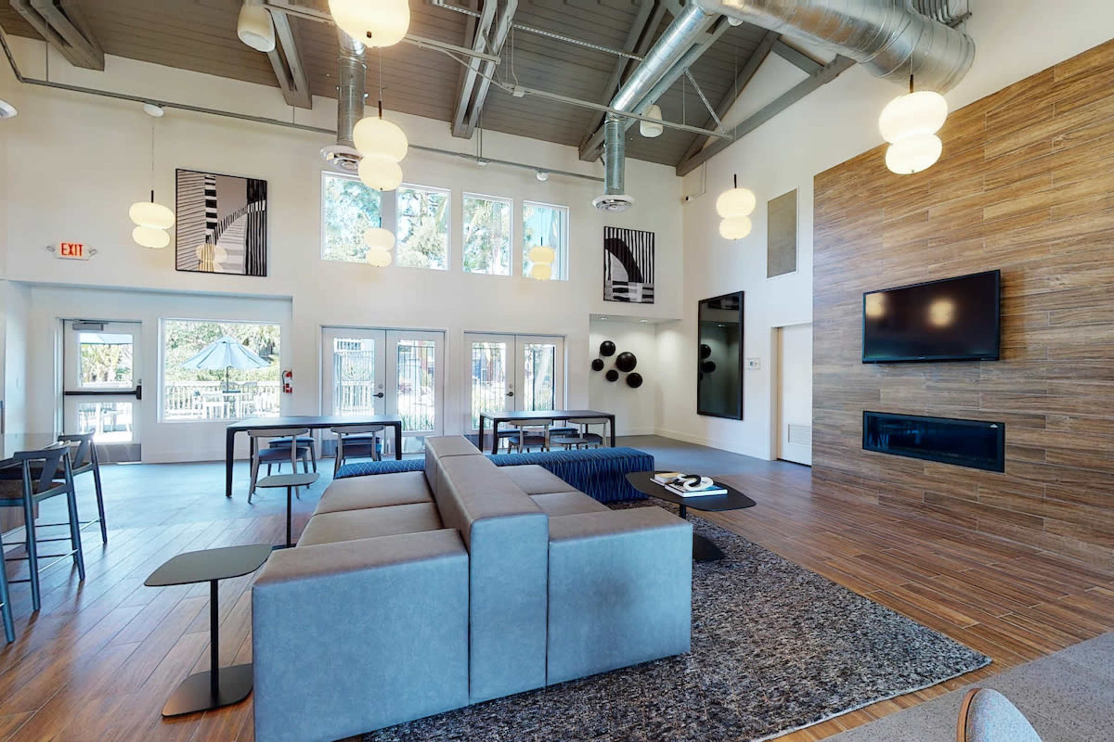 A modern lounge area with a sectional sofa, a fireplace, and large windows providing natural light.