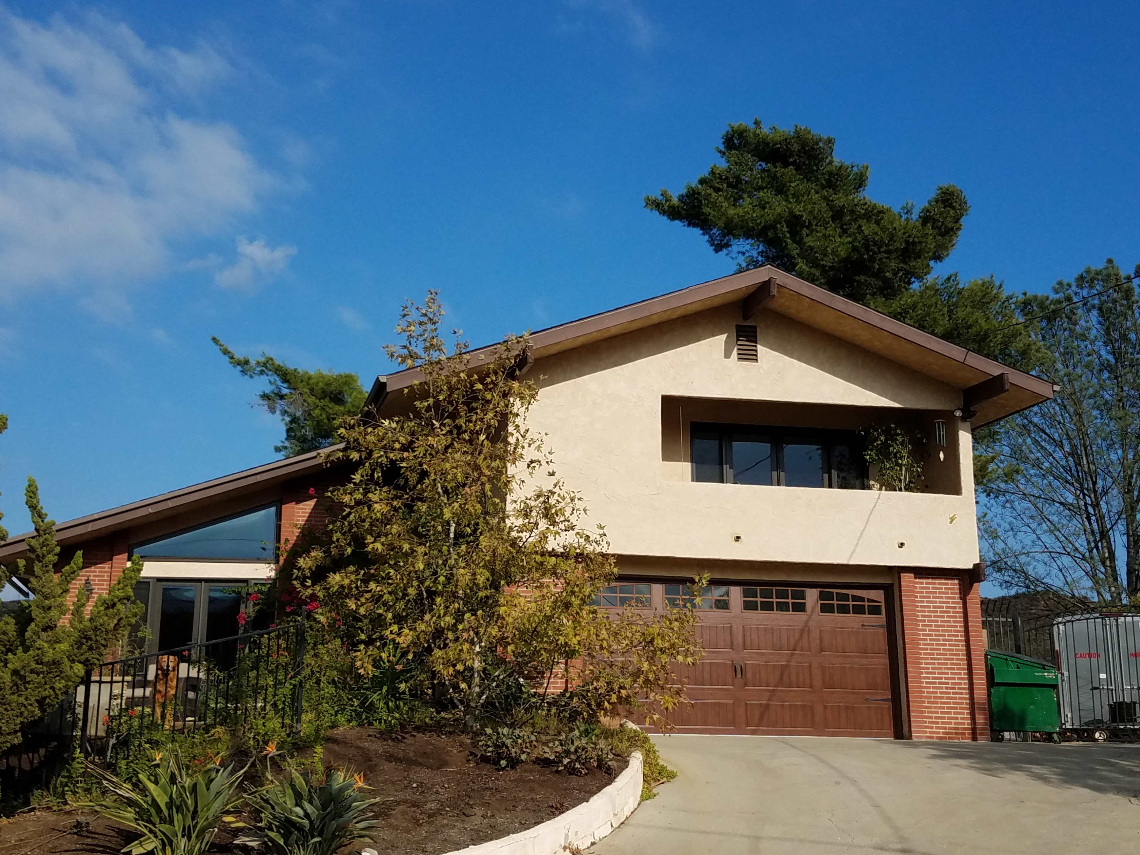 A modern two-story house with a brick and stucco exterior, featuring a garage and landscaped front yard.