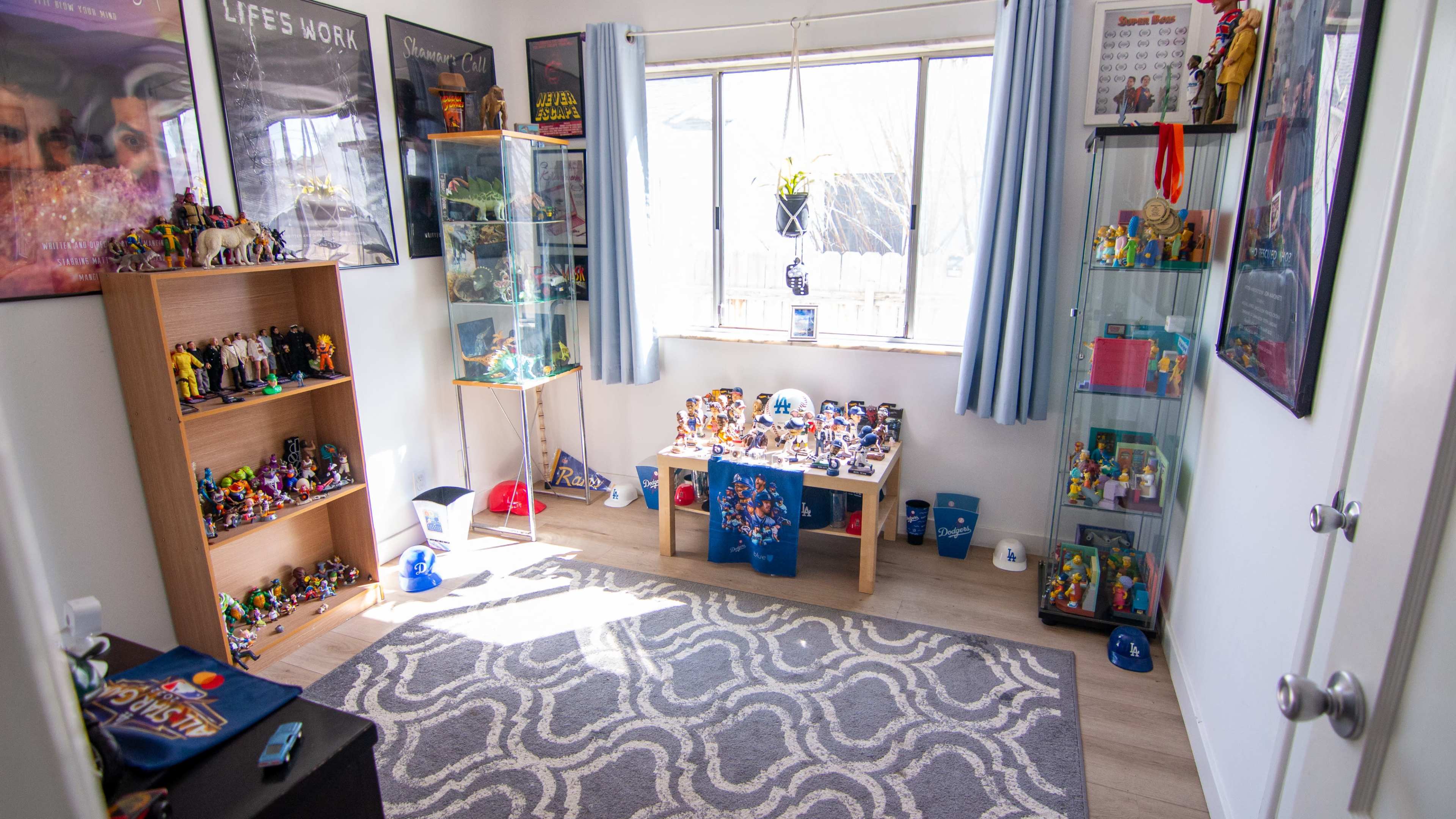 A brightly lit room featuring display shelves filled with collectibles, toys, and posters on the walls, with a patterned rug on the floor.