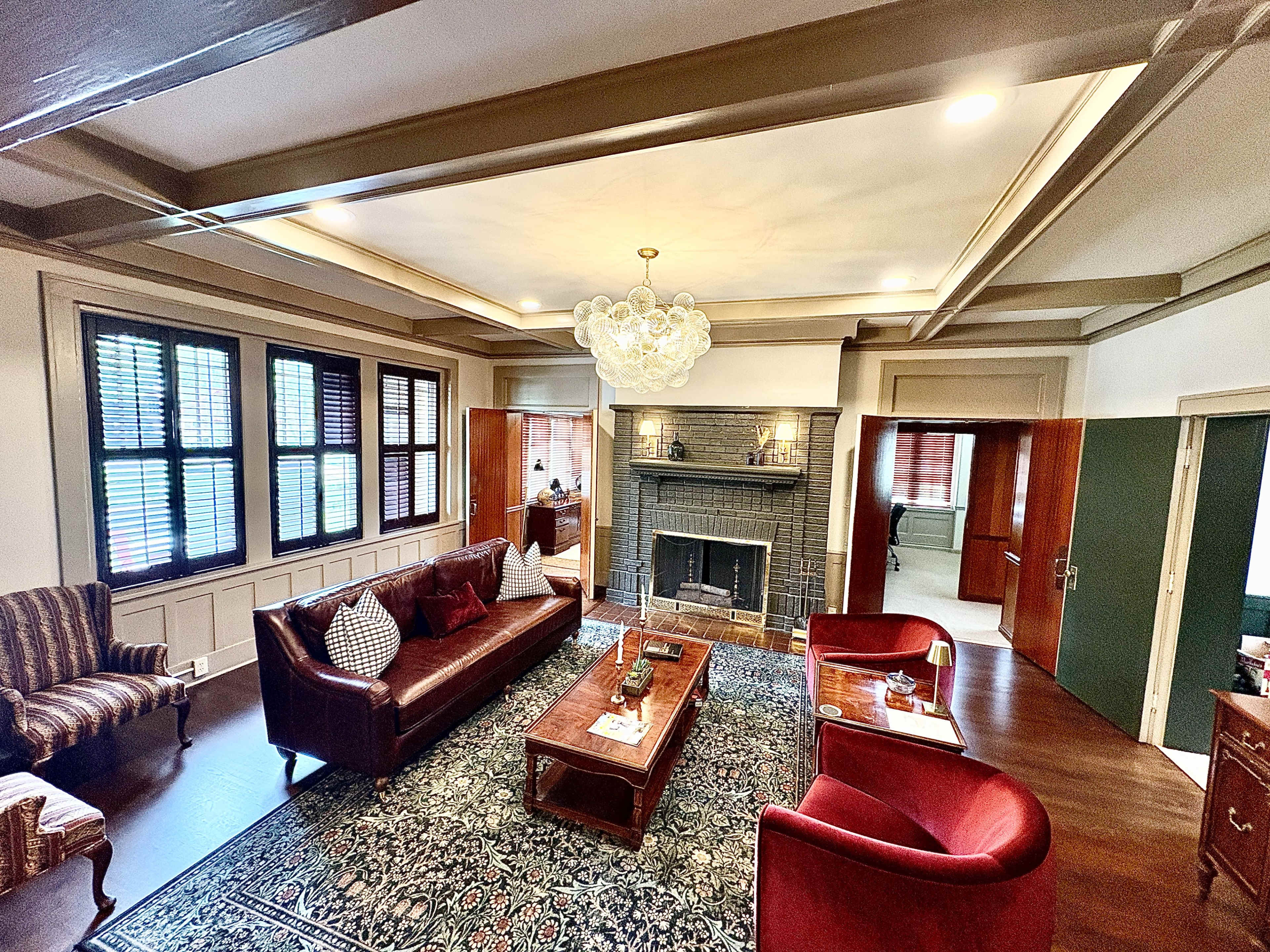 The image shows a well-furnished living room featuring two leather sofas, a wooden coffee table, and a decorative fireplace with a patterned rug on the floor.