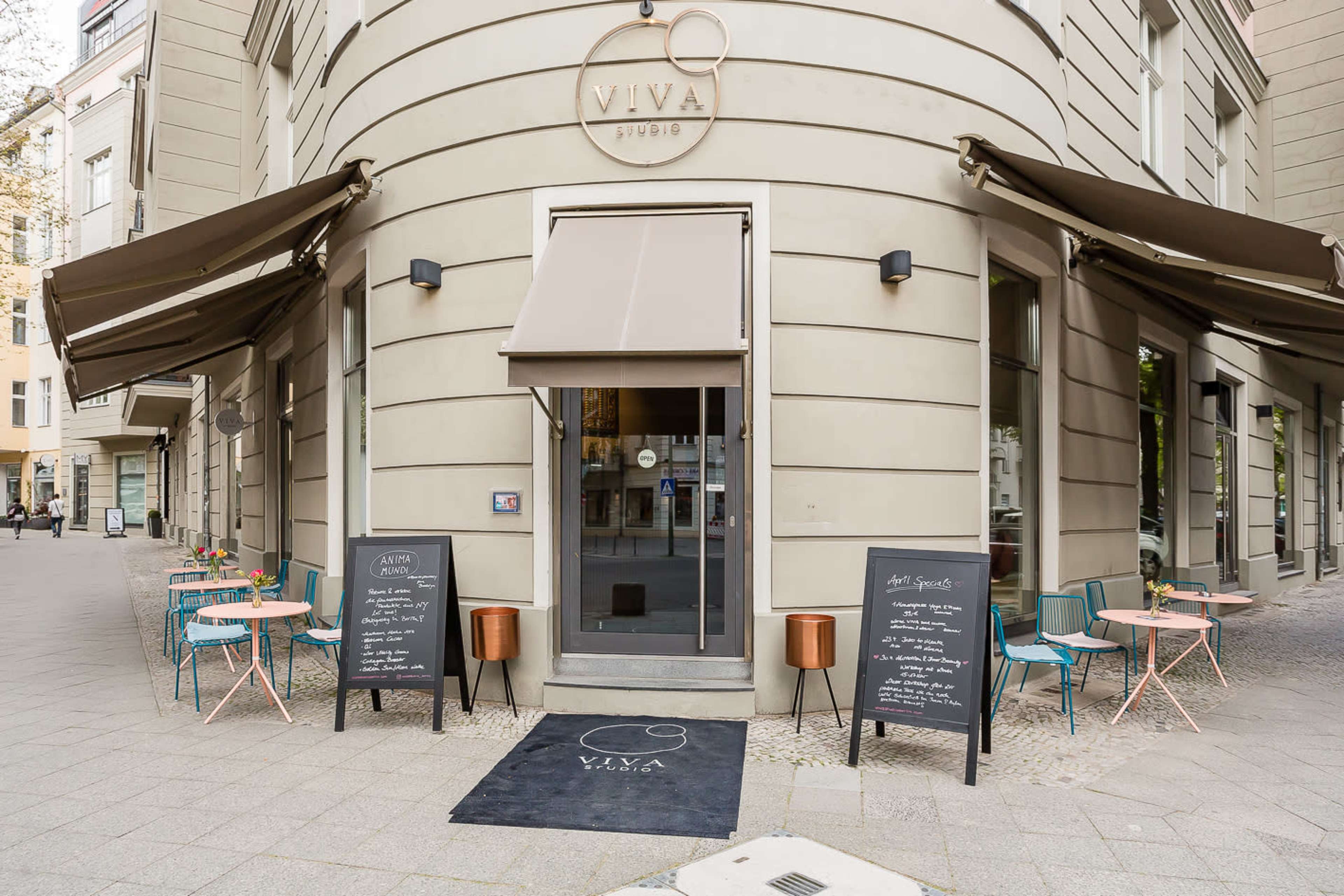 A corner café with outdoor seating, featuring colorful chairs and menus displayed on chalkboards at the entrance.